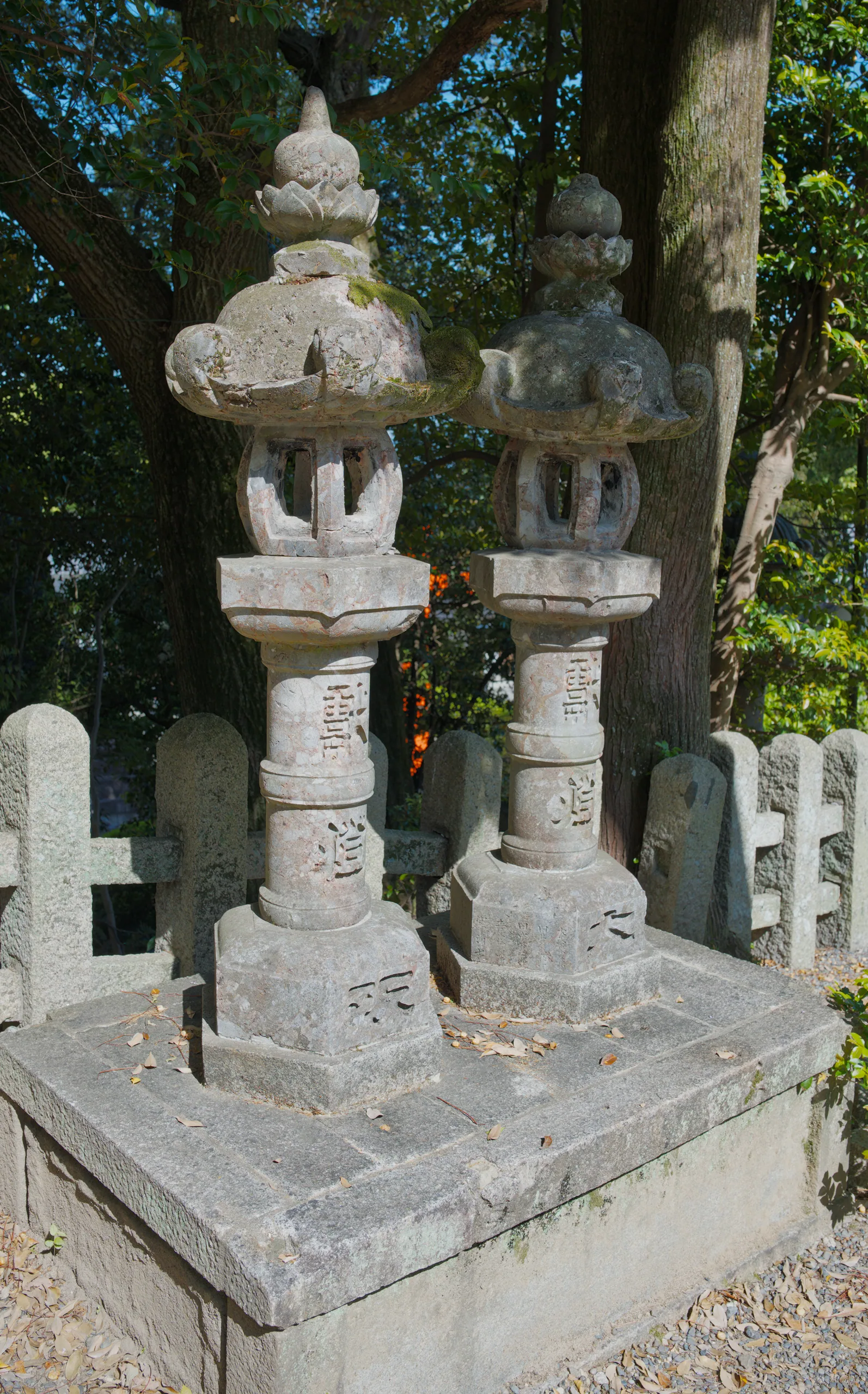 Stacked stone lanterns with a tiered pagoda-shaped top, covered in moss, standing in a temple garden.