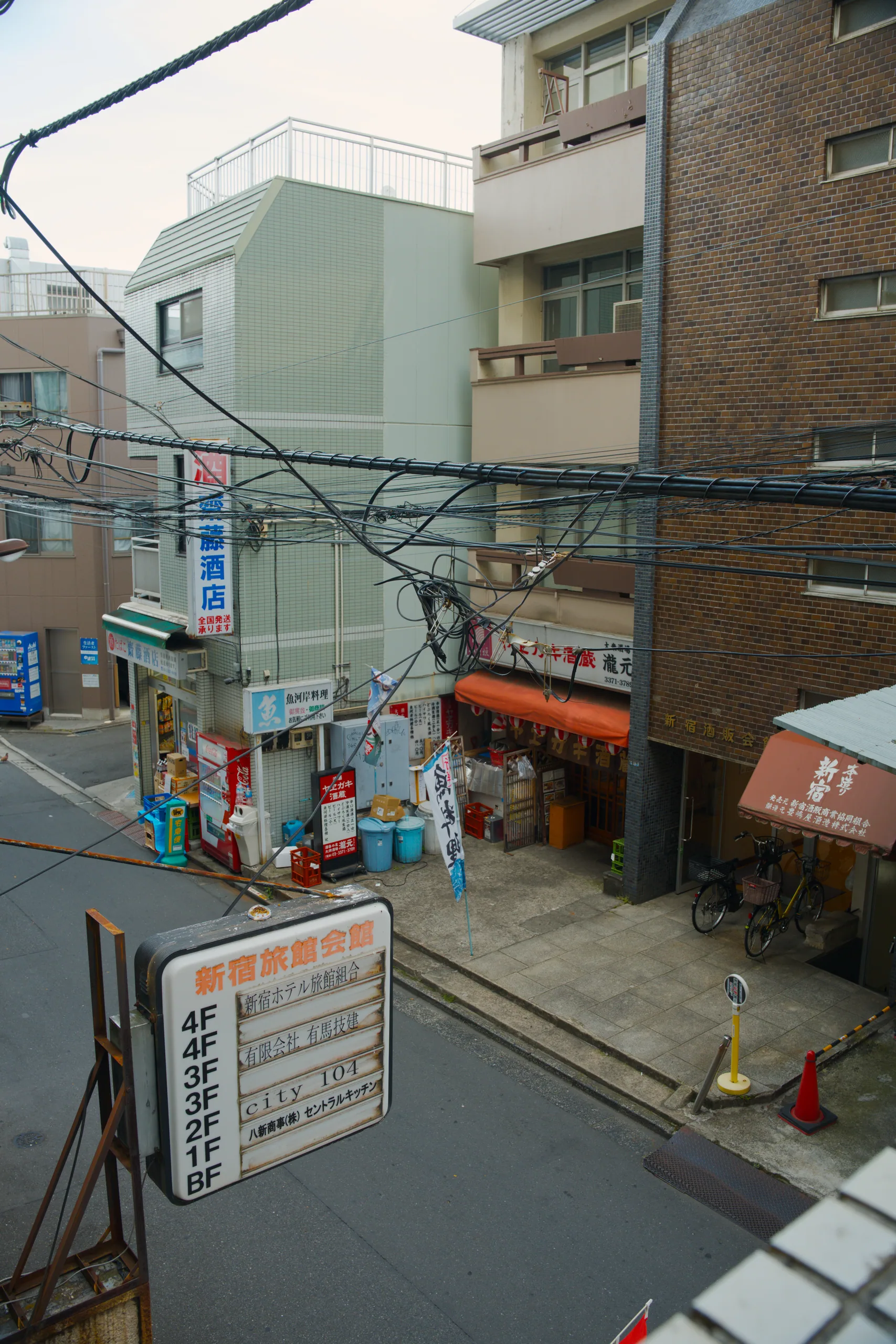 Street intersection with residential apartments above ground-floor shops, power lines crossing above.