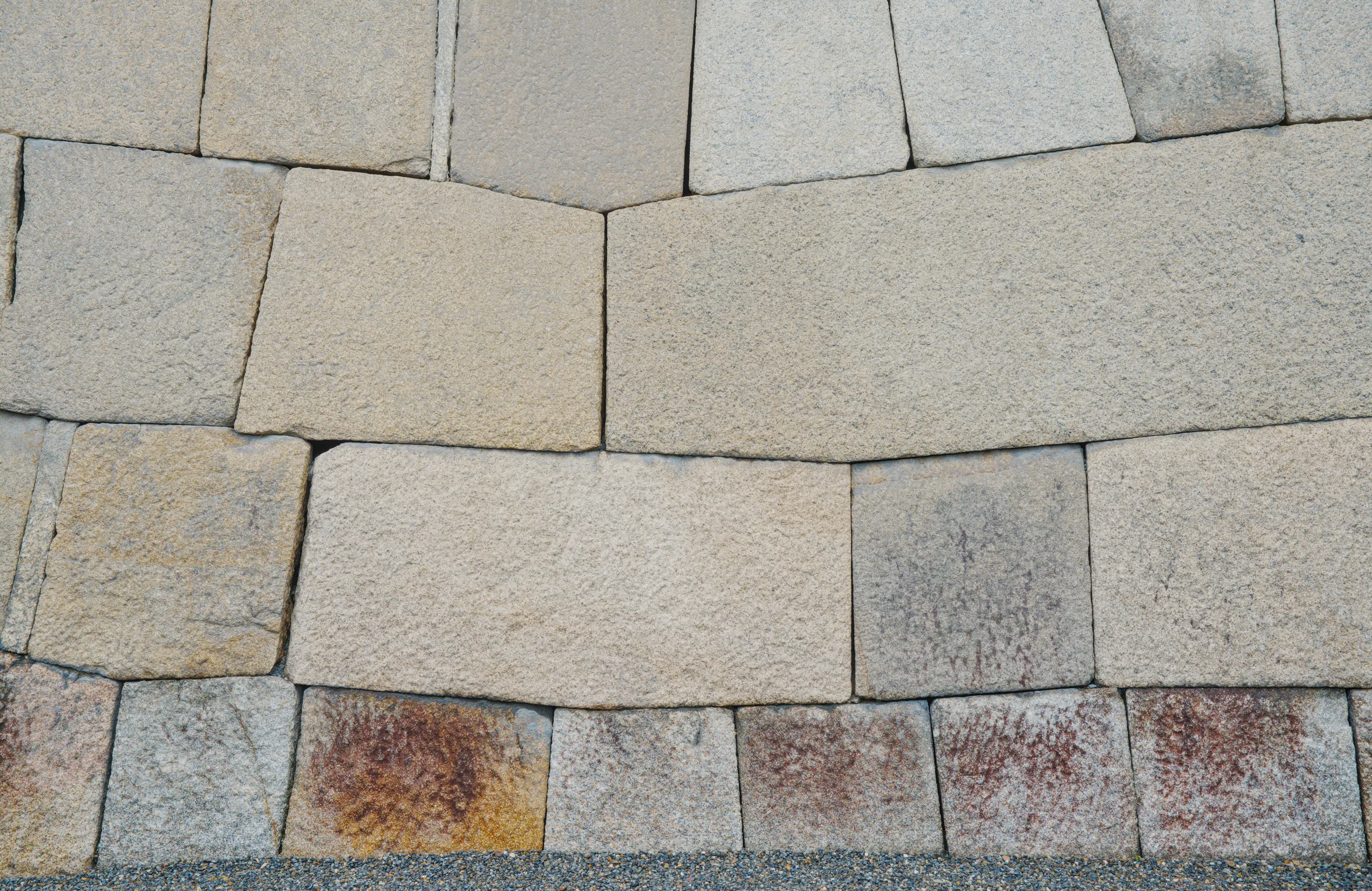Large rectangular stone blocks fitted tightly, some weathered to rust and orange tones.