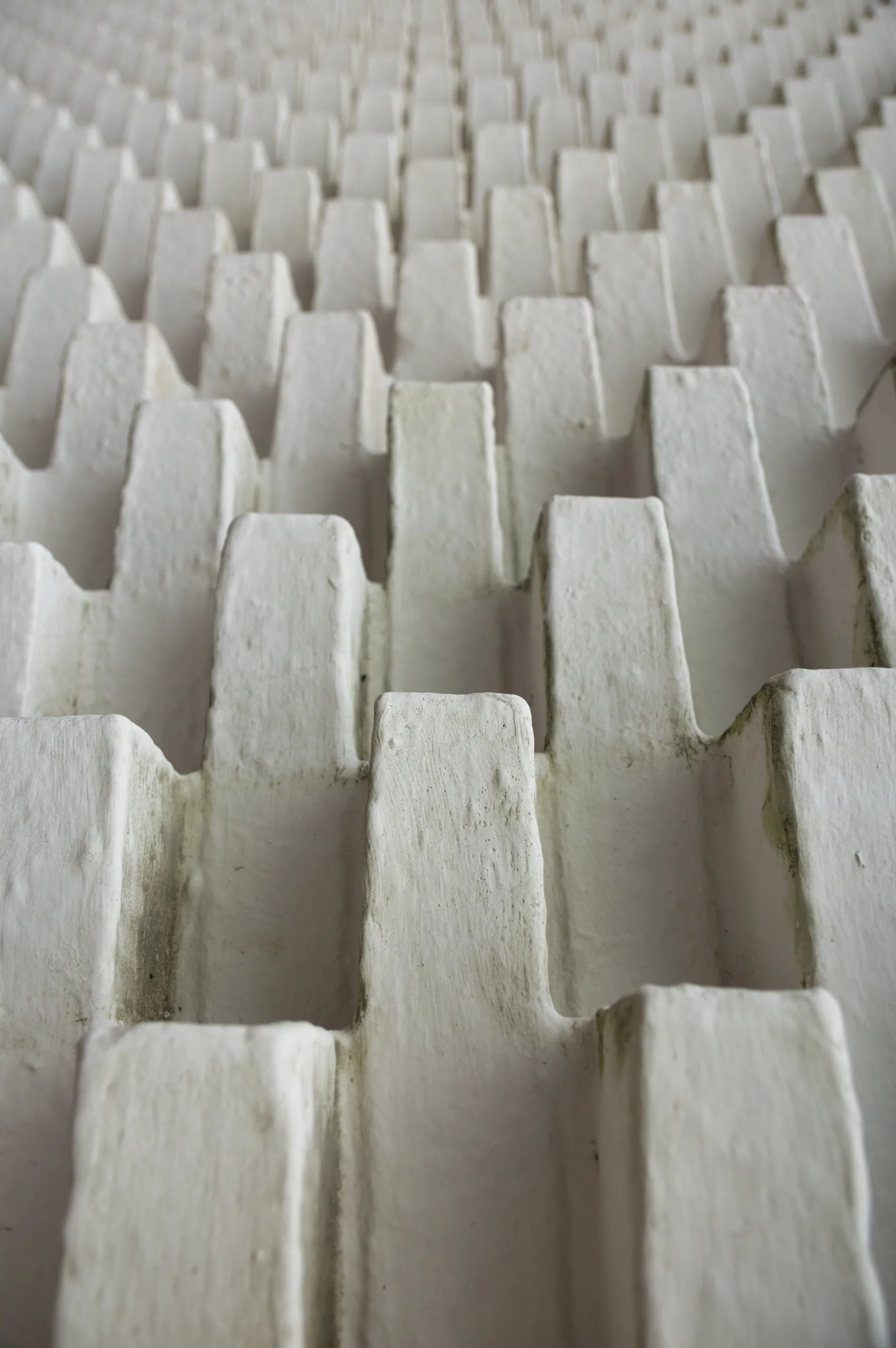 A close view of a white architectural relief of repeating stepped blocks receding into shadow.