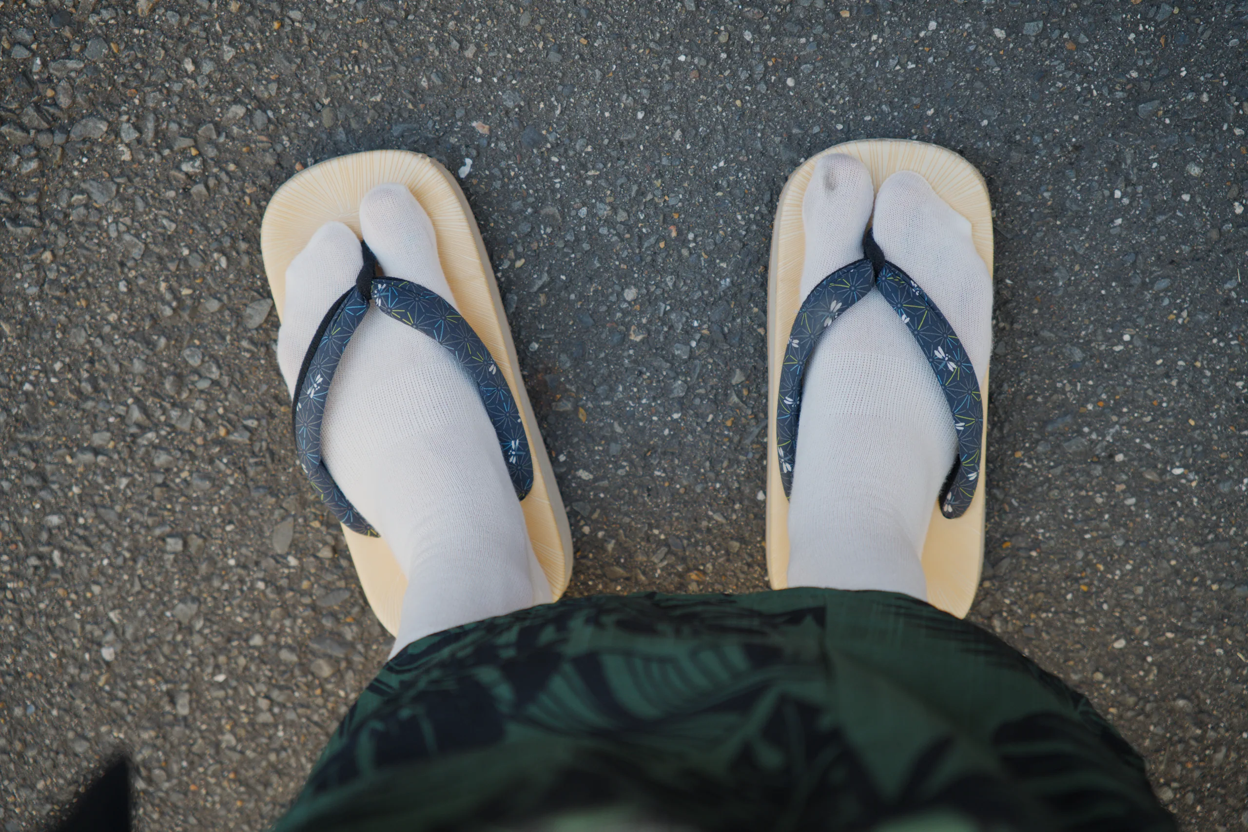 Traditional sandals viewed from above on textured gray pavement.