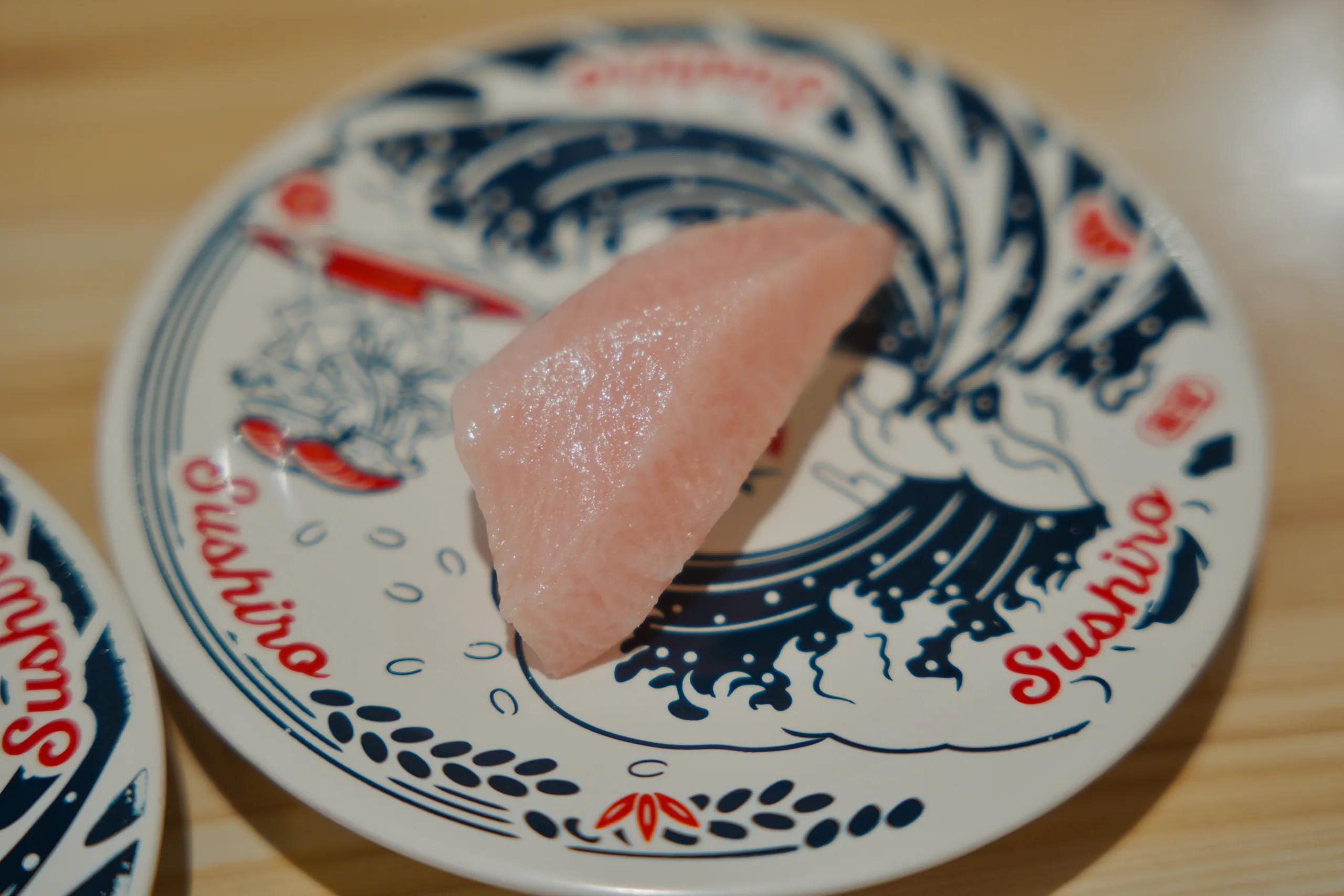 A piece of fish on an ornately decorated porcelain dish with blue and red painted patterns.