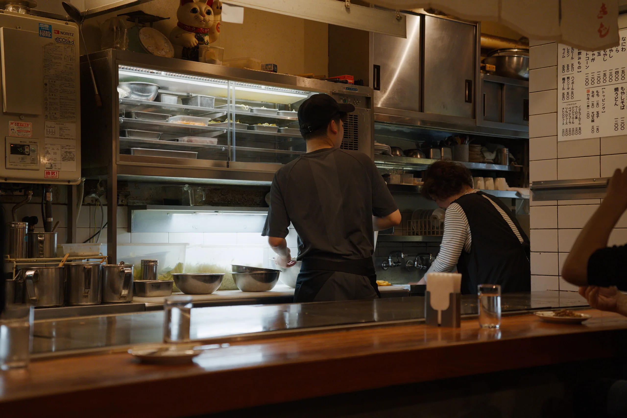 Chefs working in a restaurant kitchen behind a counter.