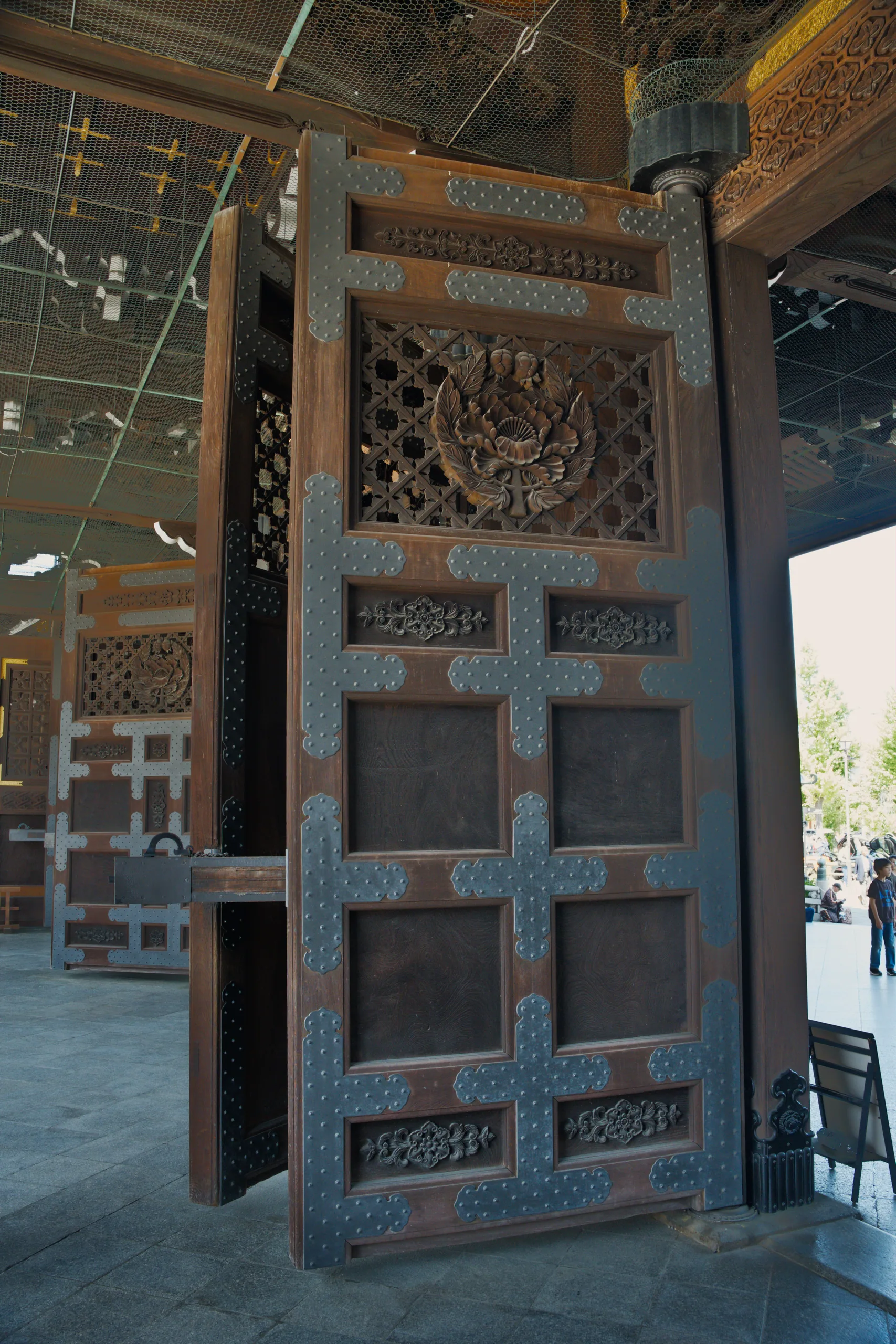 A weathered wooden door with blue-green paint and geometric lattice panels set into stone.