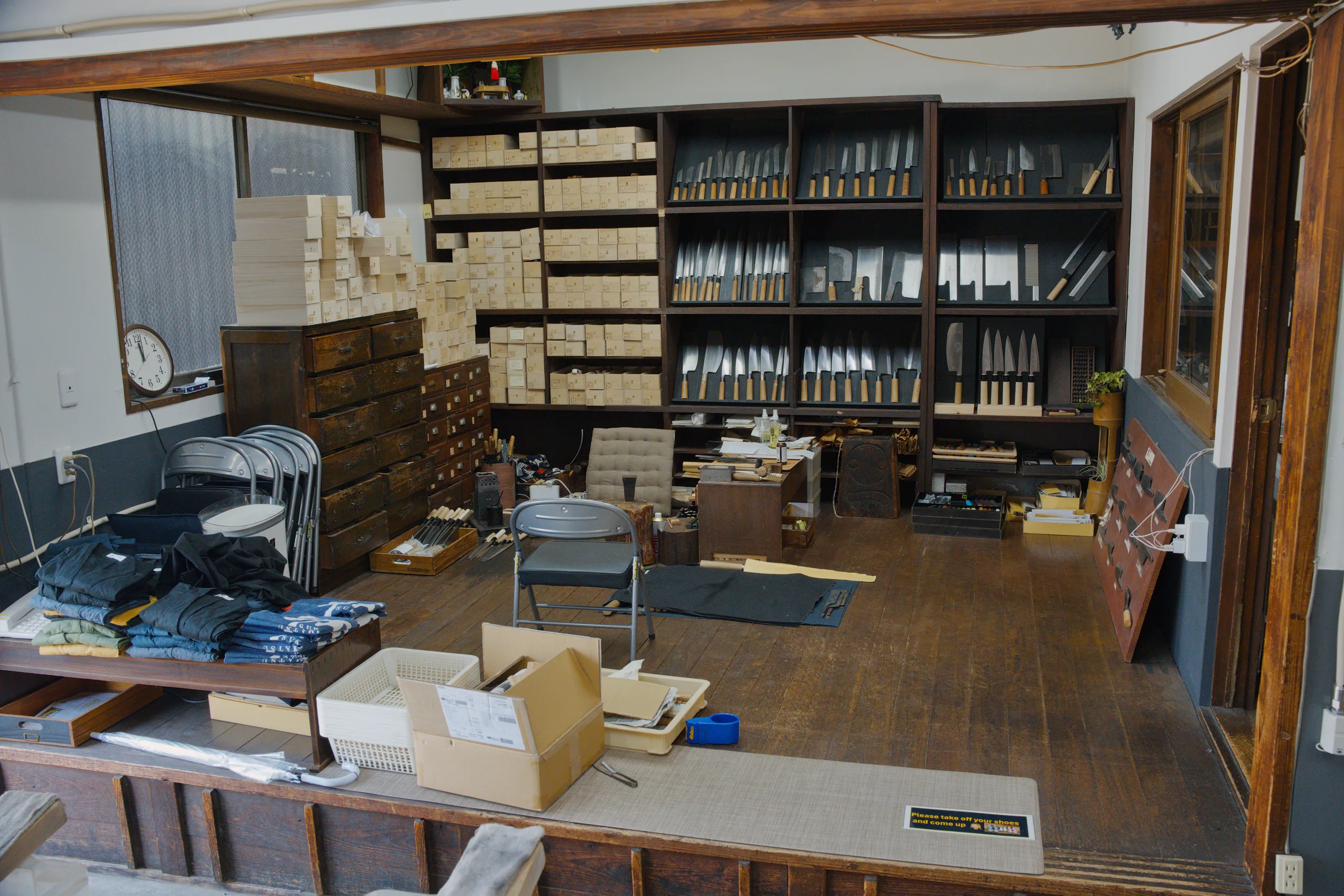 Interior space with wooden shelving units and glass-fronted display cabinets filled with organized tools or implements.