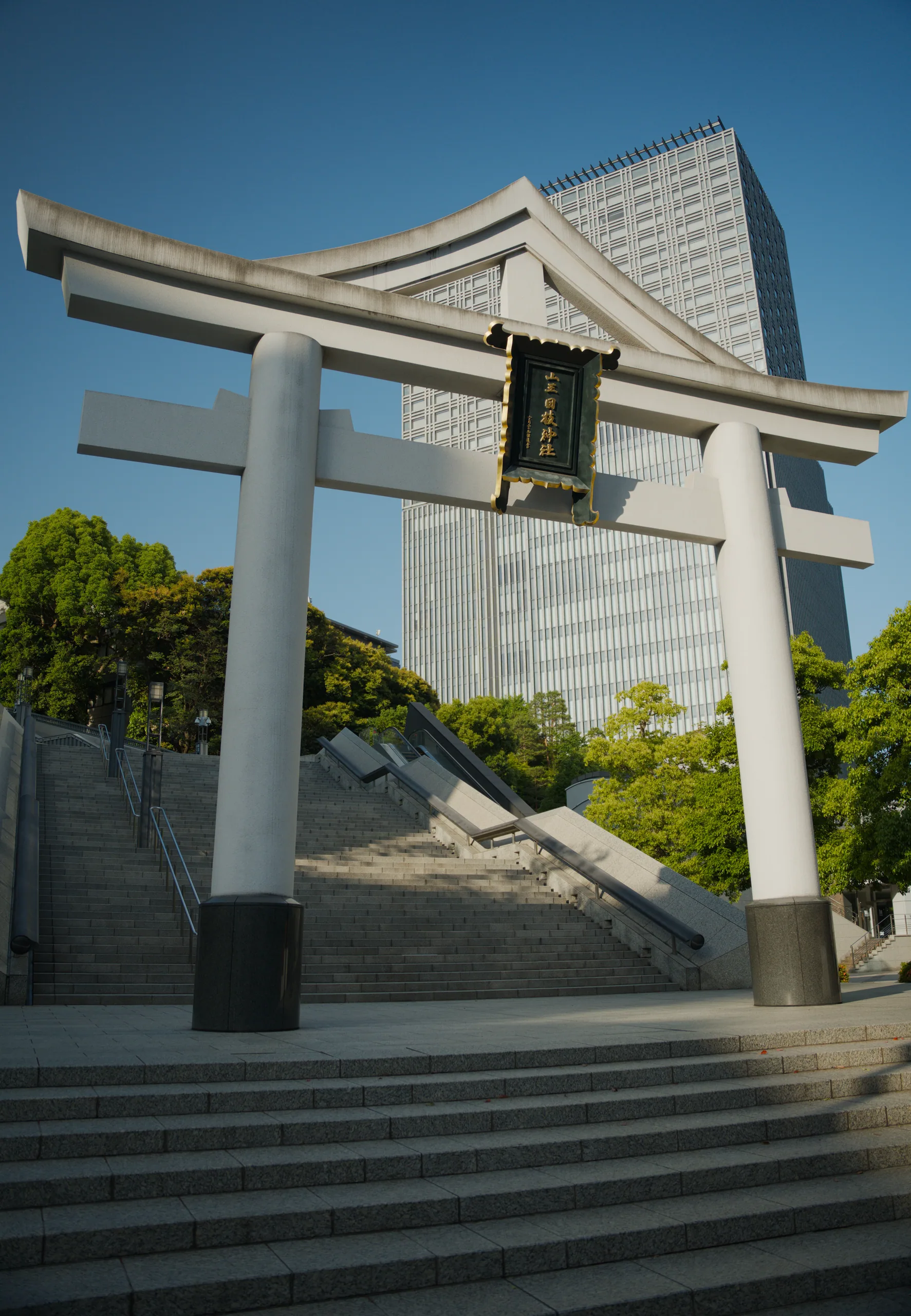 A white pillared gate structure standing in bright sunlight against clear blue sky.