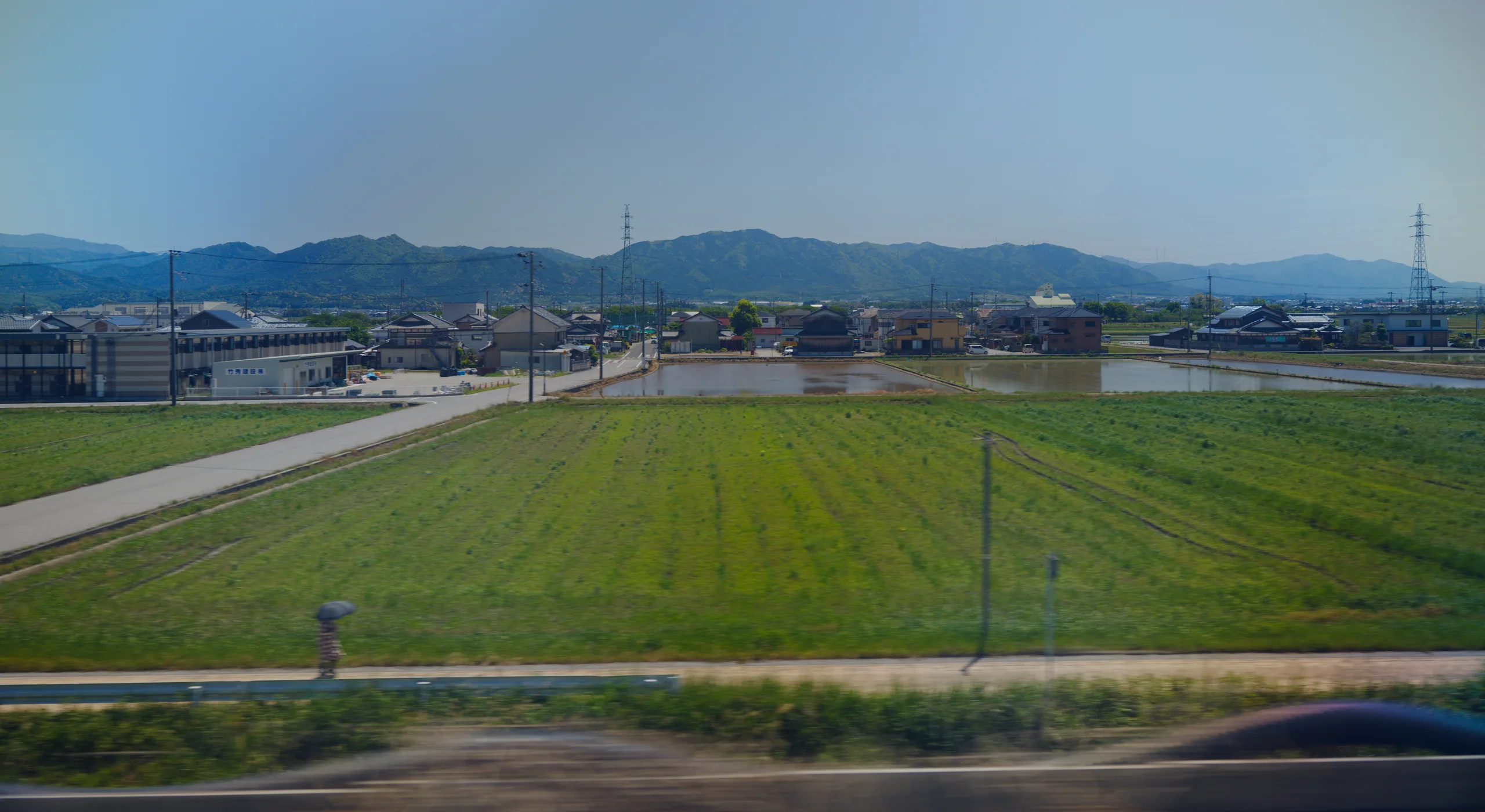 Agricultural fields and mountains viewed through a train window.