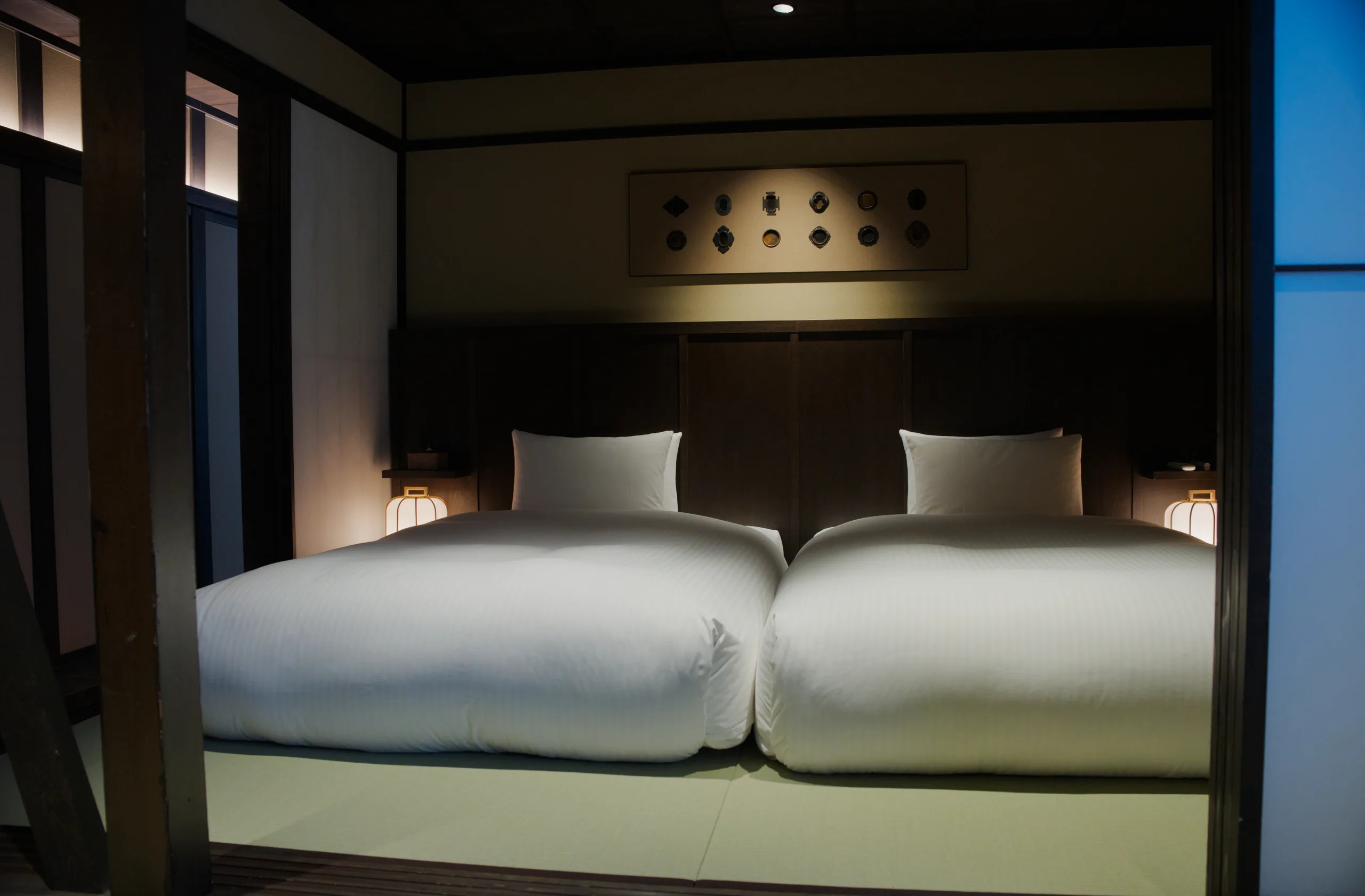 Hotel bedroom with white pillows and ambient wall-mounted lighting.