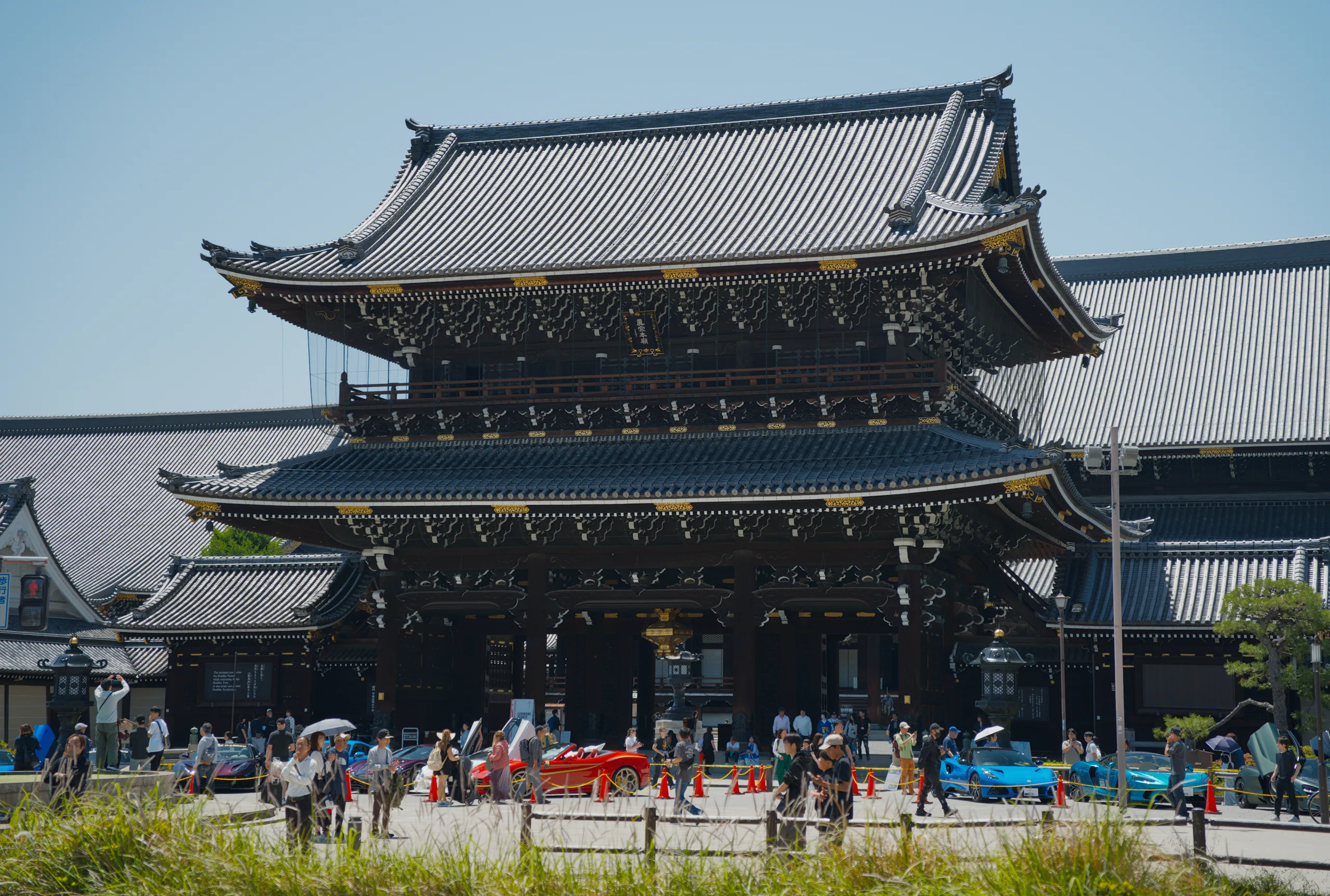 A two-tiered Japanese temple with upturned eaves surrounded by crowds of visitors.