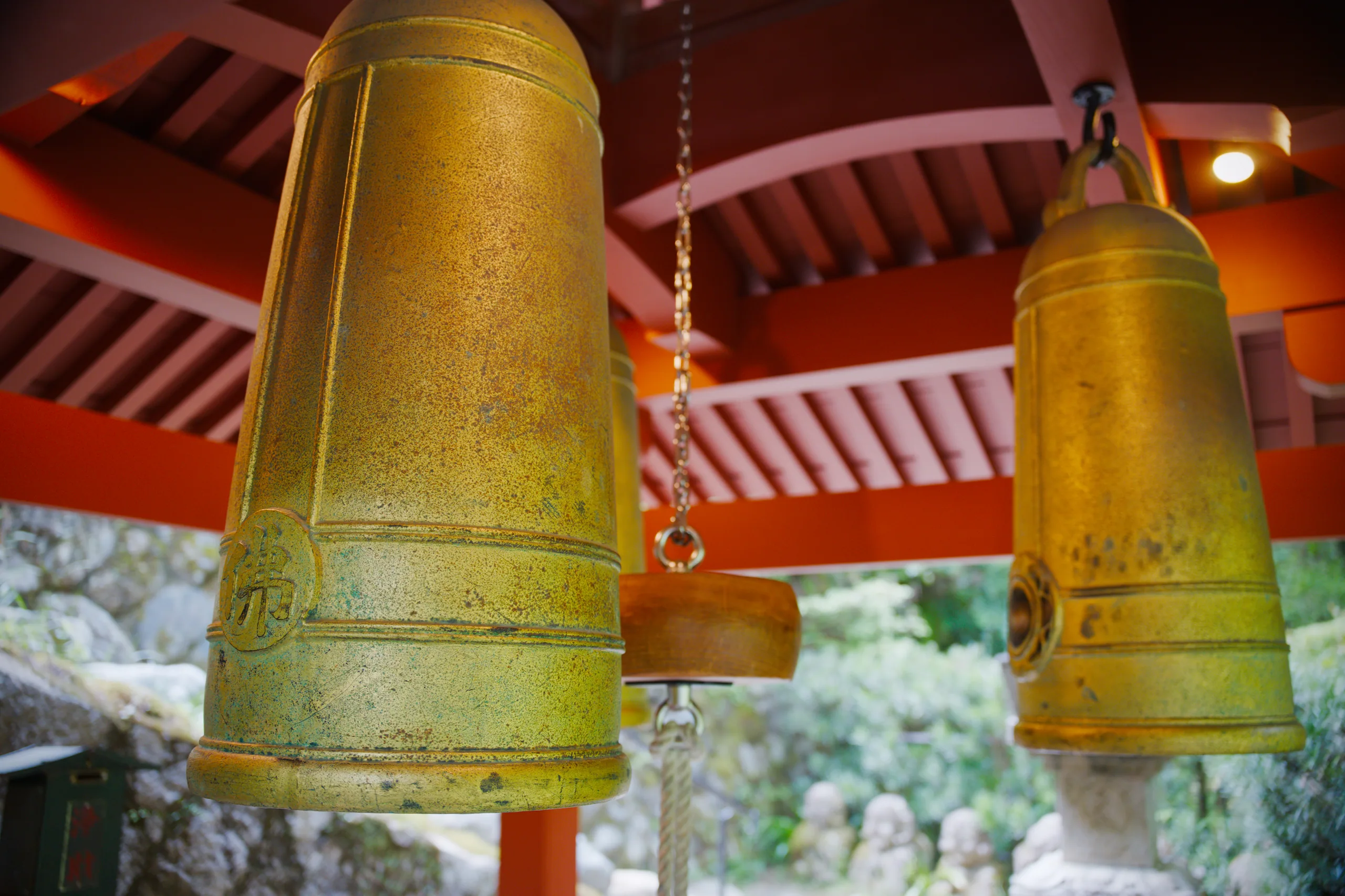Golden bronze bells hanging beneath a red temple structure.
