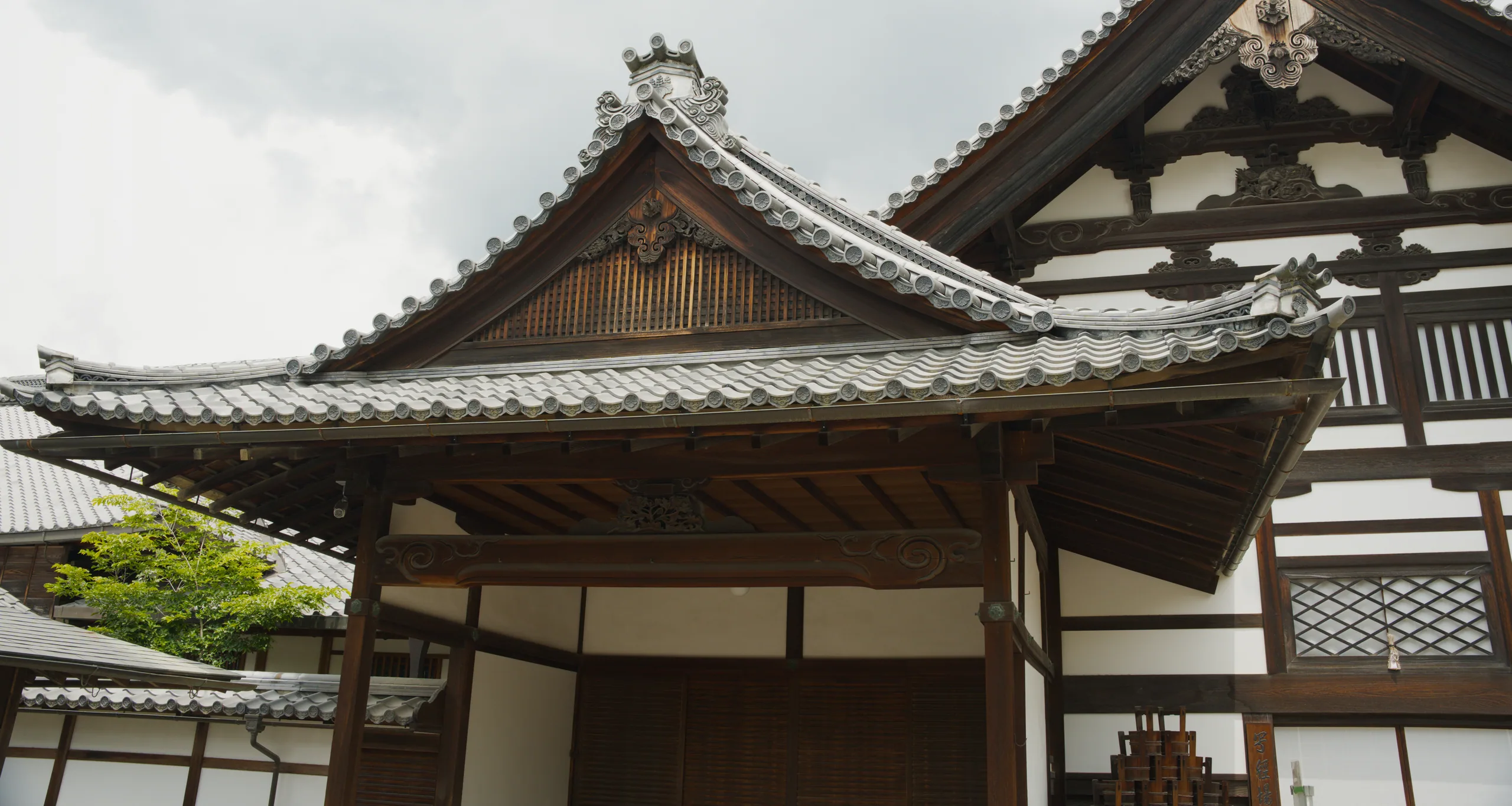 The curved golden-tiled roof of a Japanese temple pavilion with ornamental ceramic ridge-end finials.