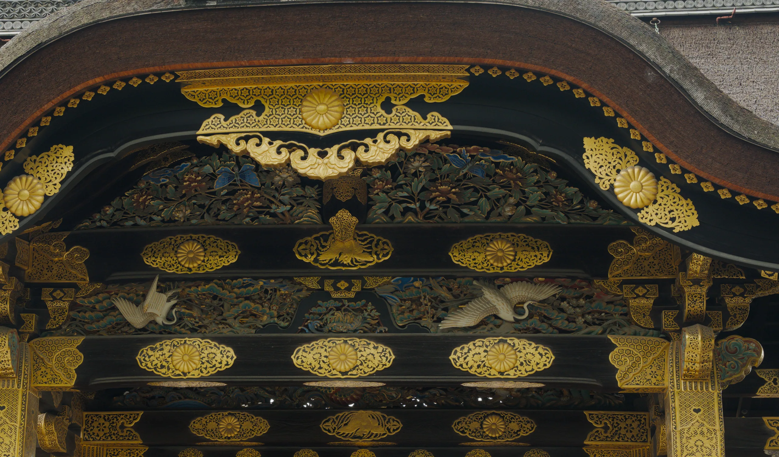Ornate wooden panel with gilded circular motifs arranged in rows on dark wood.