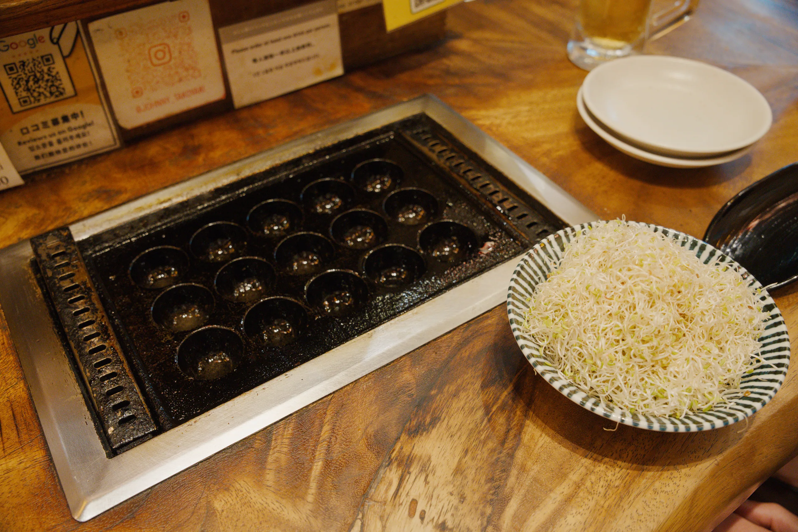 Compartmentalized box of chocolates on a wooden table next to a white plate.