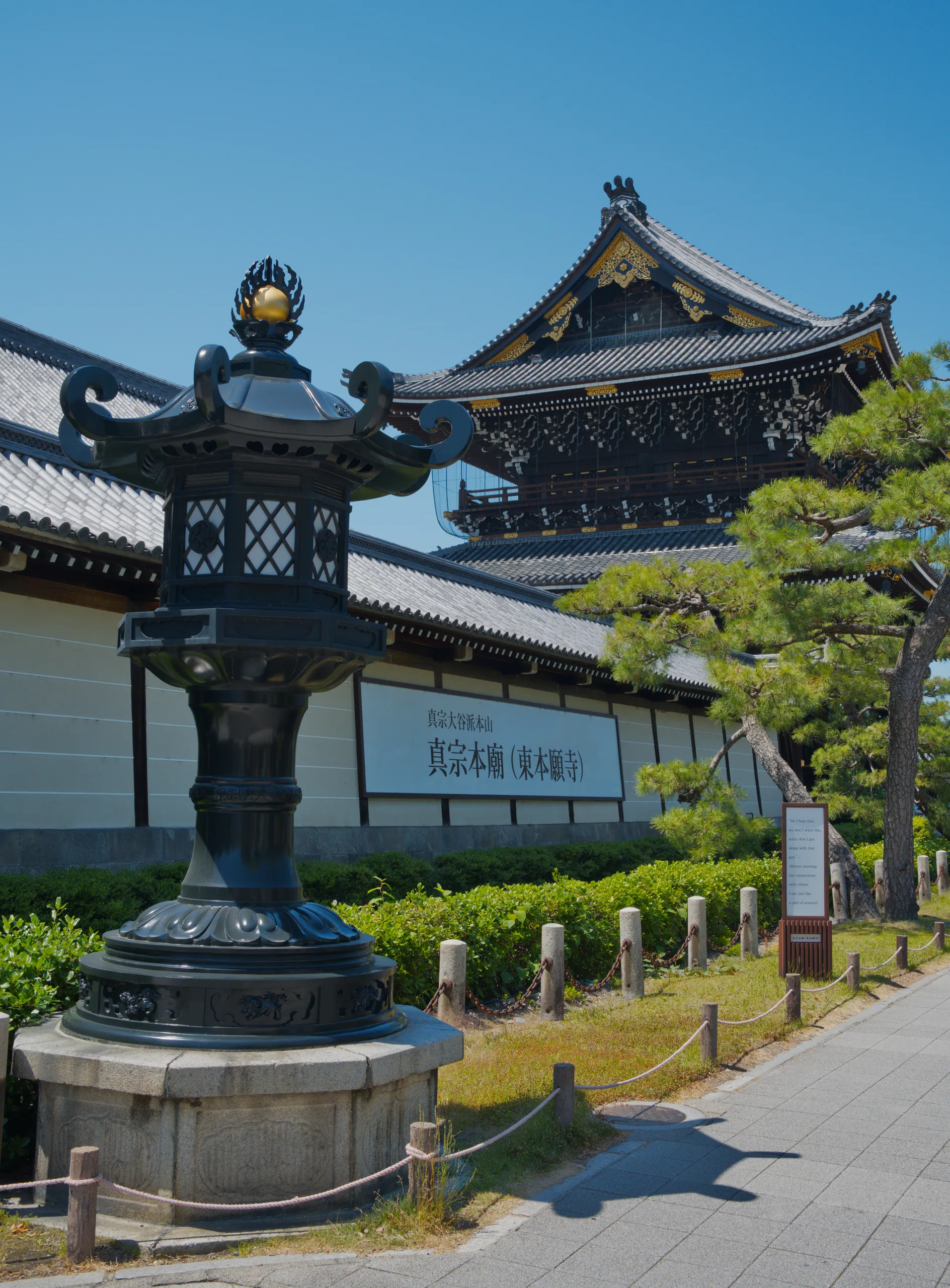 A temple building with an upturned curved roof, a bronze figure on the peak, and white railings.