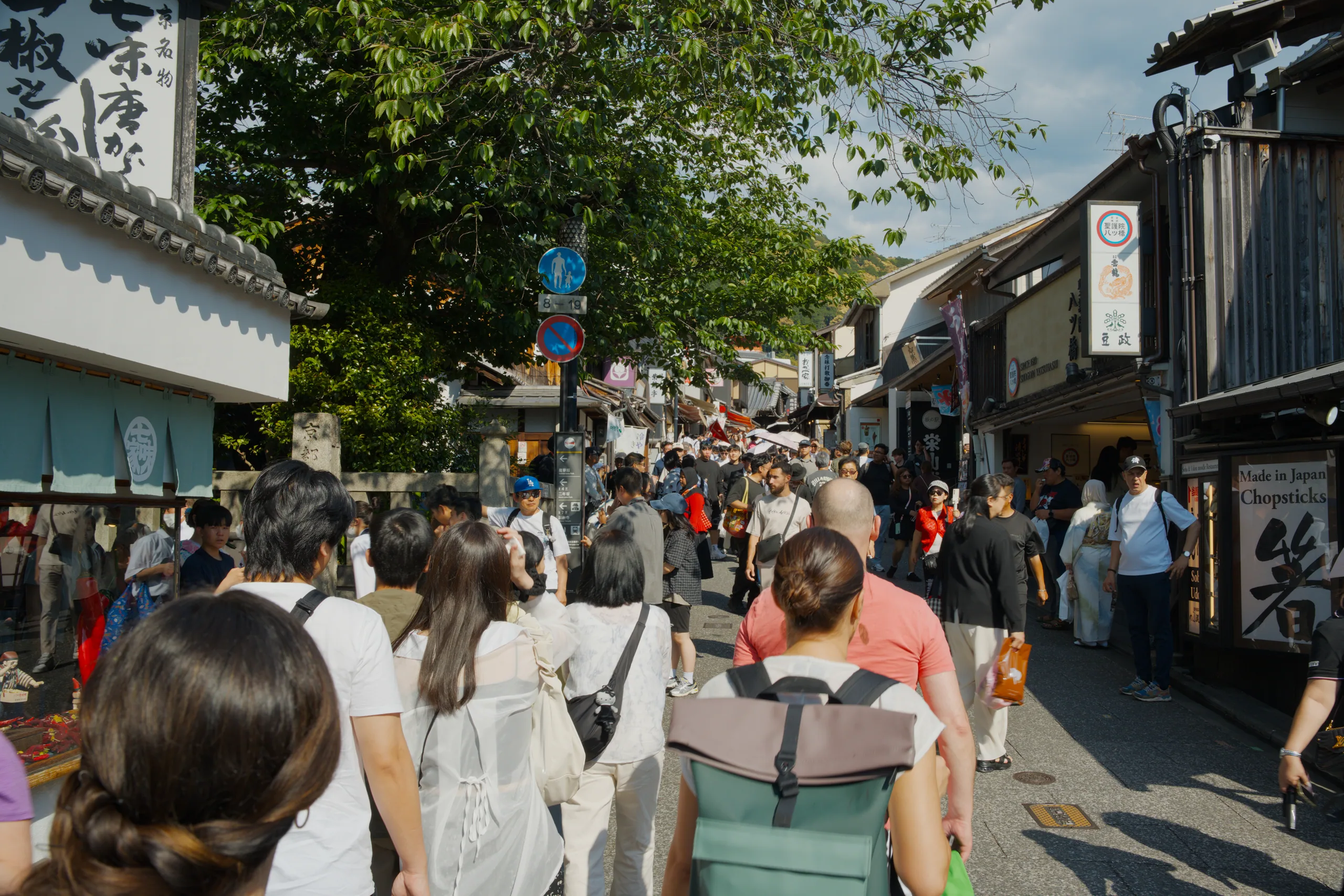 A crowded shopping street lined with trees and storefronts.