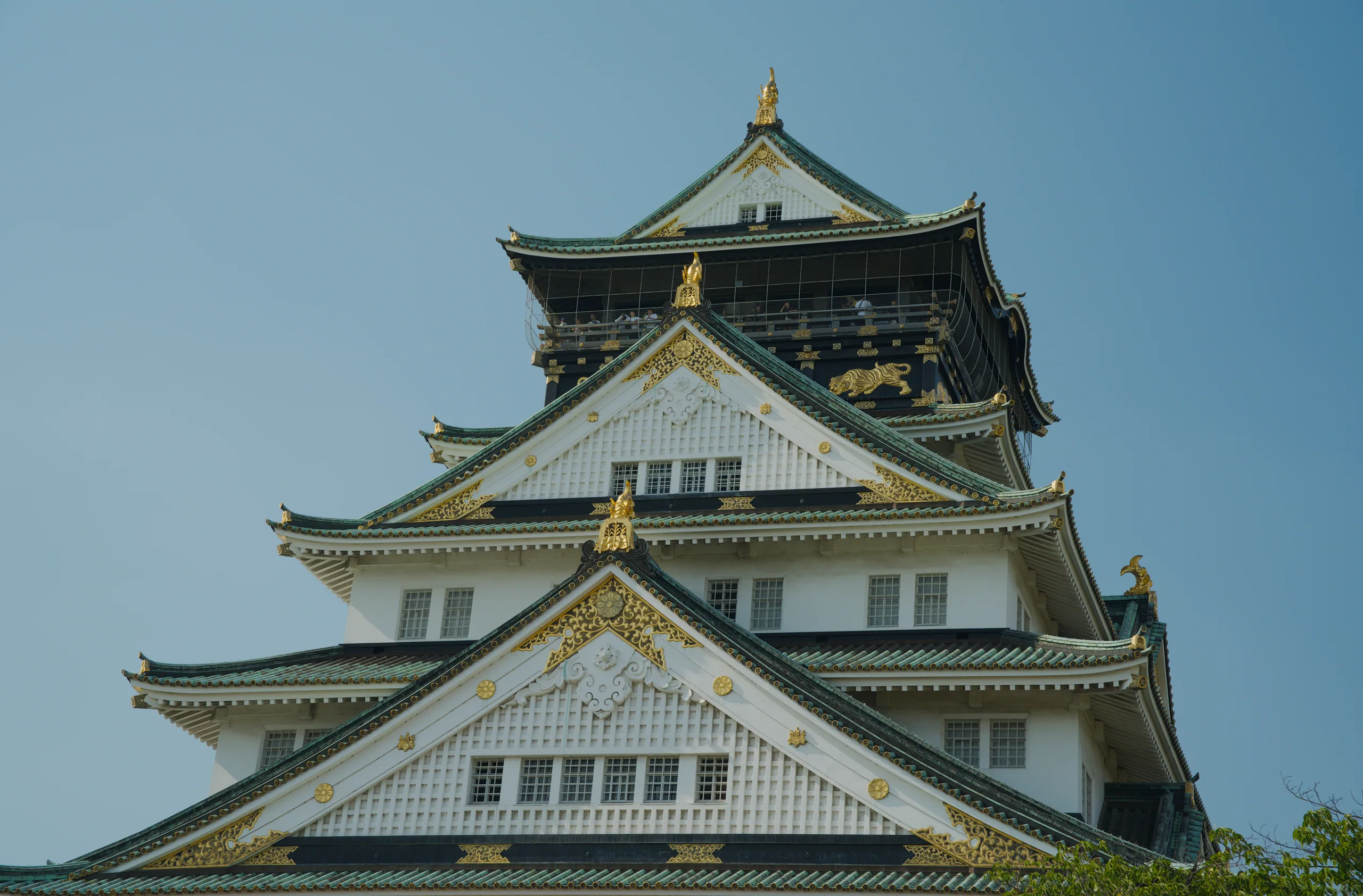 Close view of layered Japanese castle roofs with upturned eaves and dark tiles creating repeating geometric tiers.