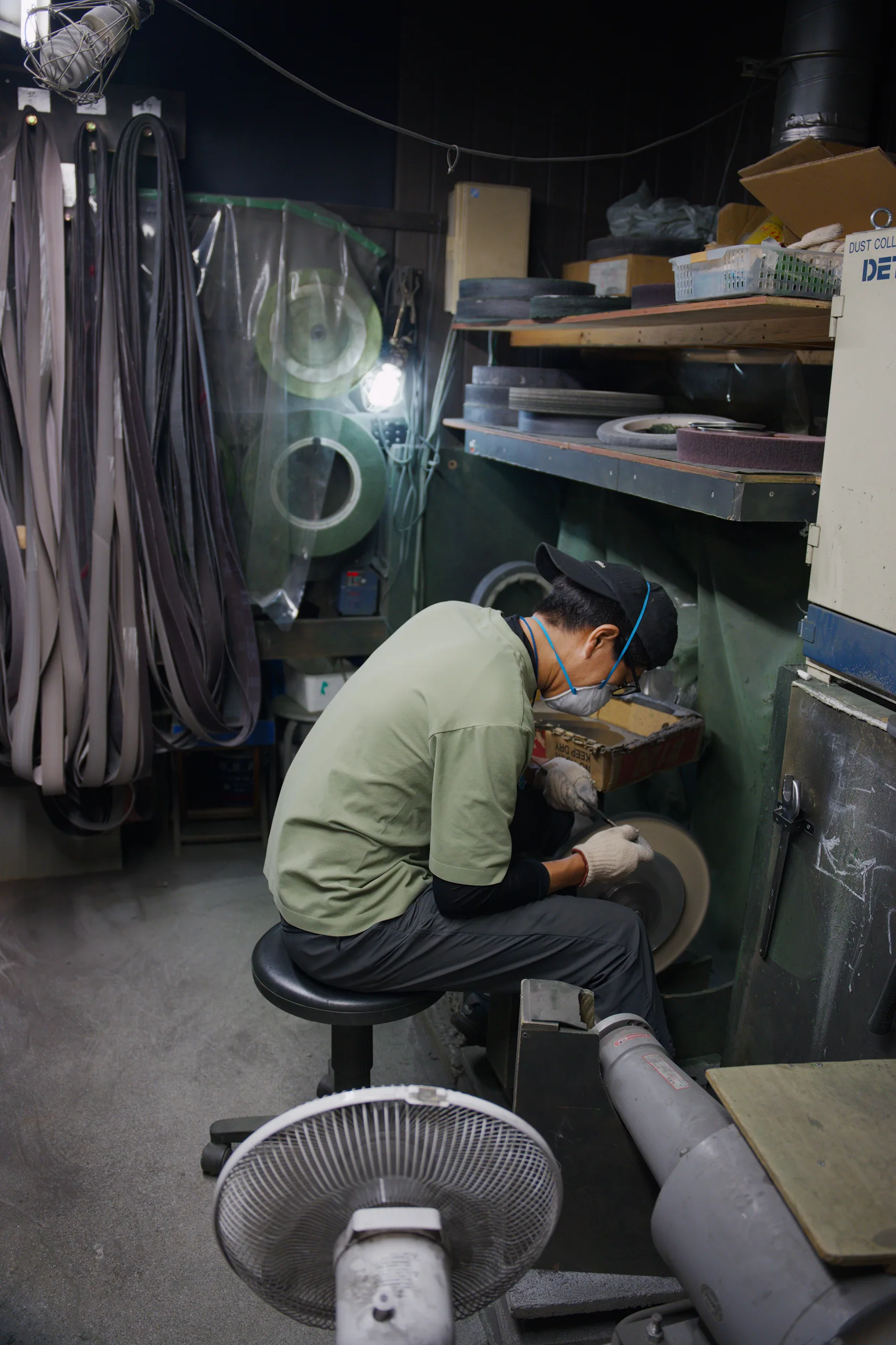 A person in a green shirt crouches beside industrial machinery and equipment.