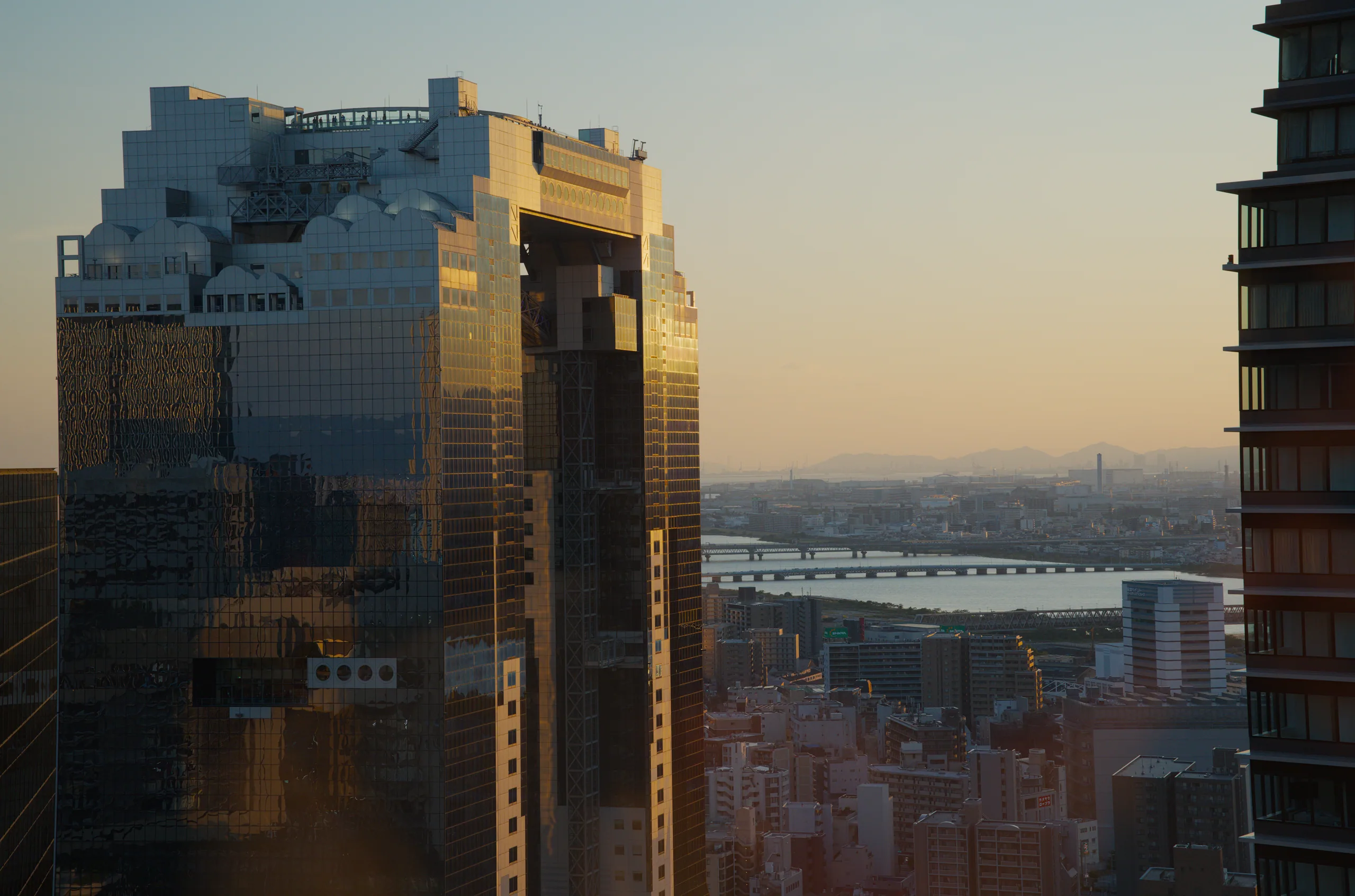Tall buildings of an urban skyline lit by golden afternoon light, viewed from a high vantage point.