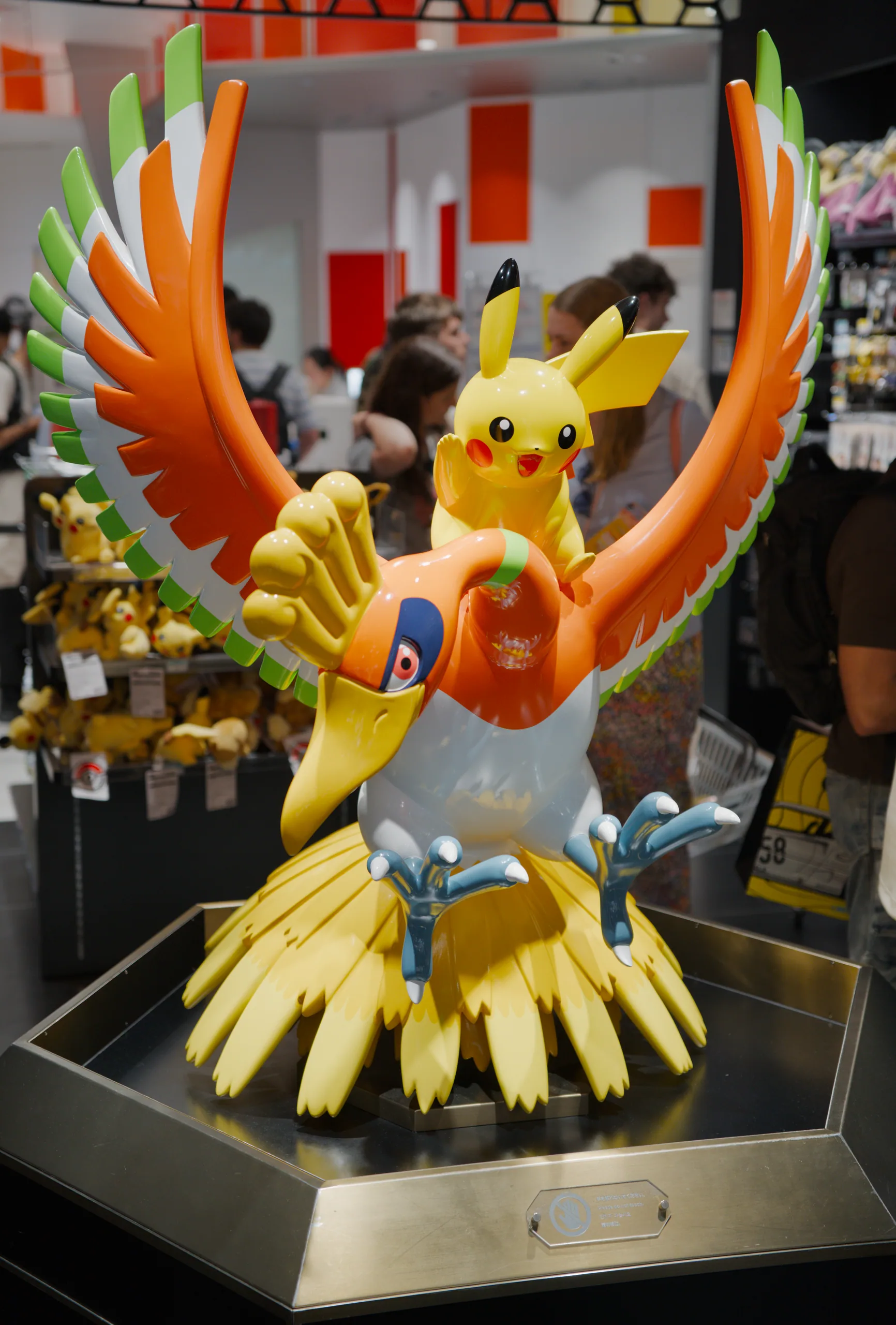 A large figure with a yellow body and spread orange wings stands in a shop window display.