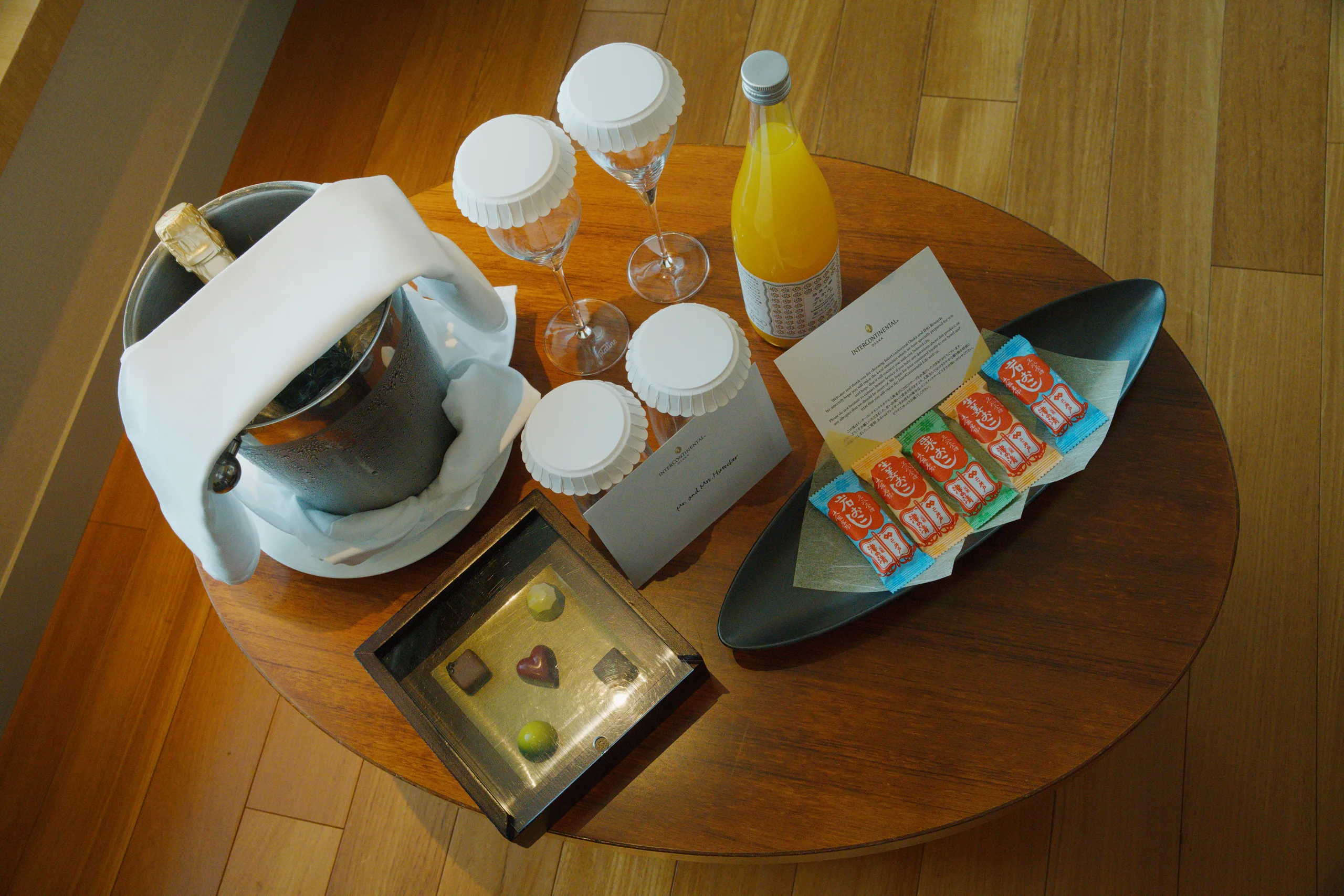 Breakfast spread on a round wooden table with coffee, juice, cups, and crackers, viewed from above.