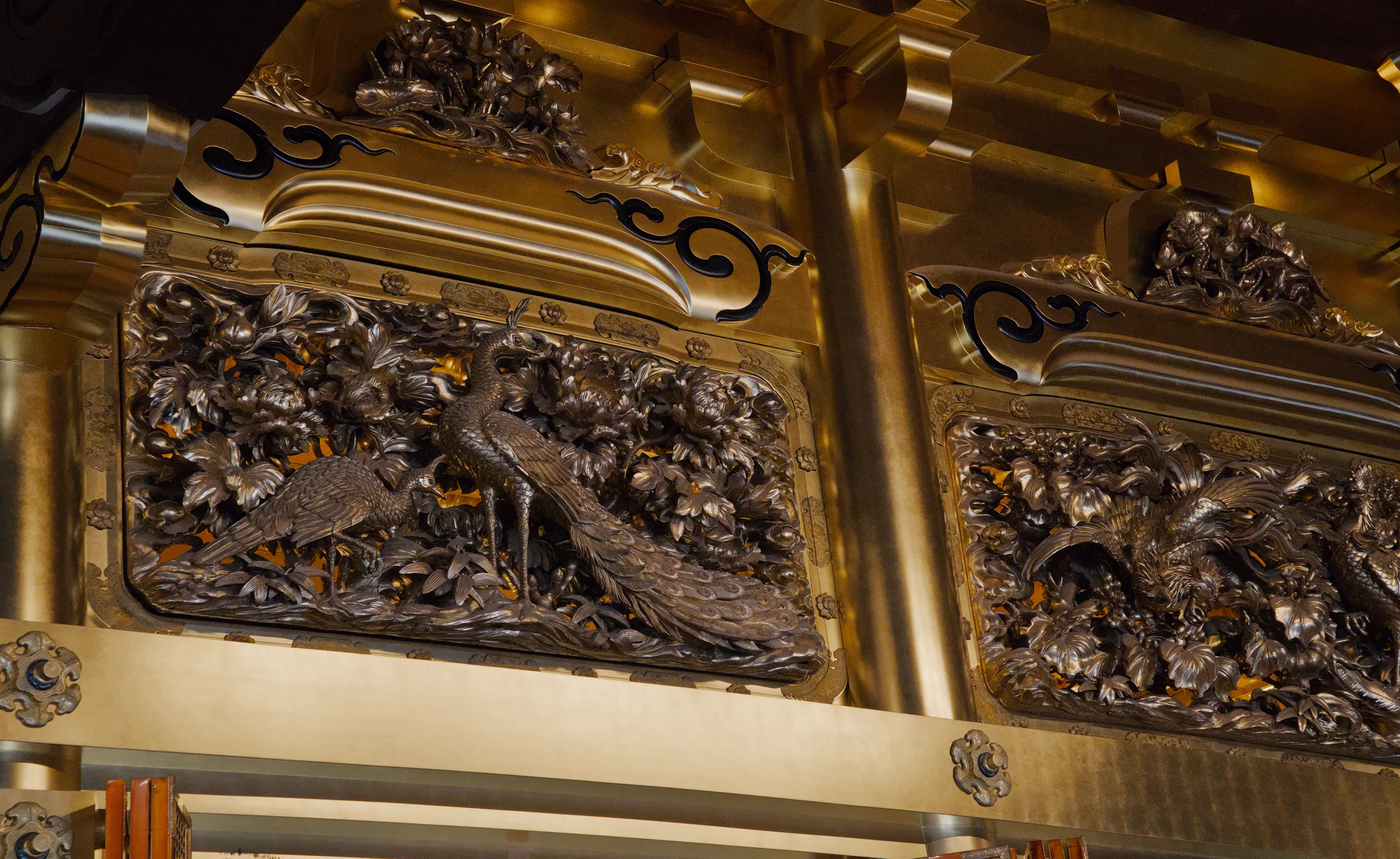 Gold carved relief sculpture showing figures rendered in ornate detail.