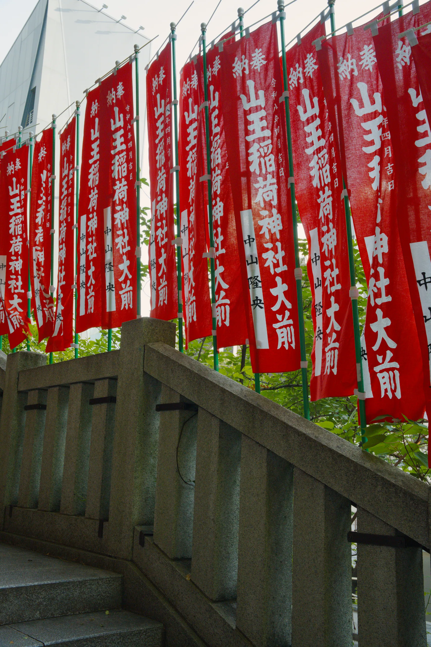 Red fabric banners with white characters hanging from a wooden shrine eave.