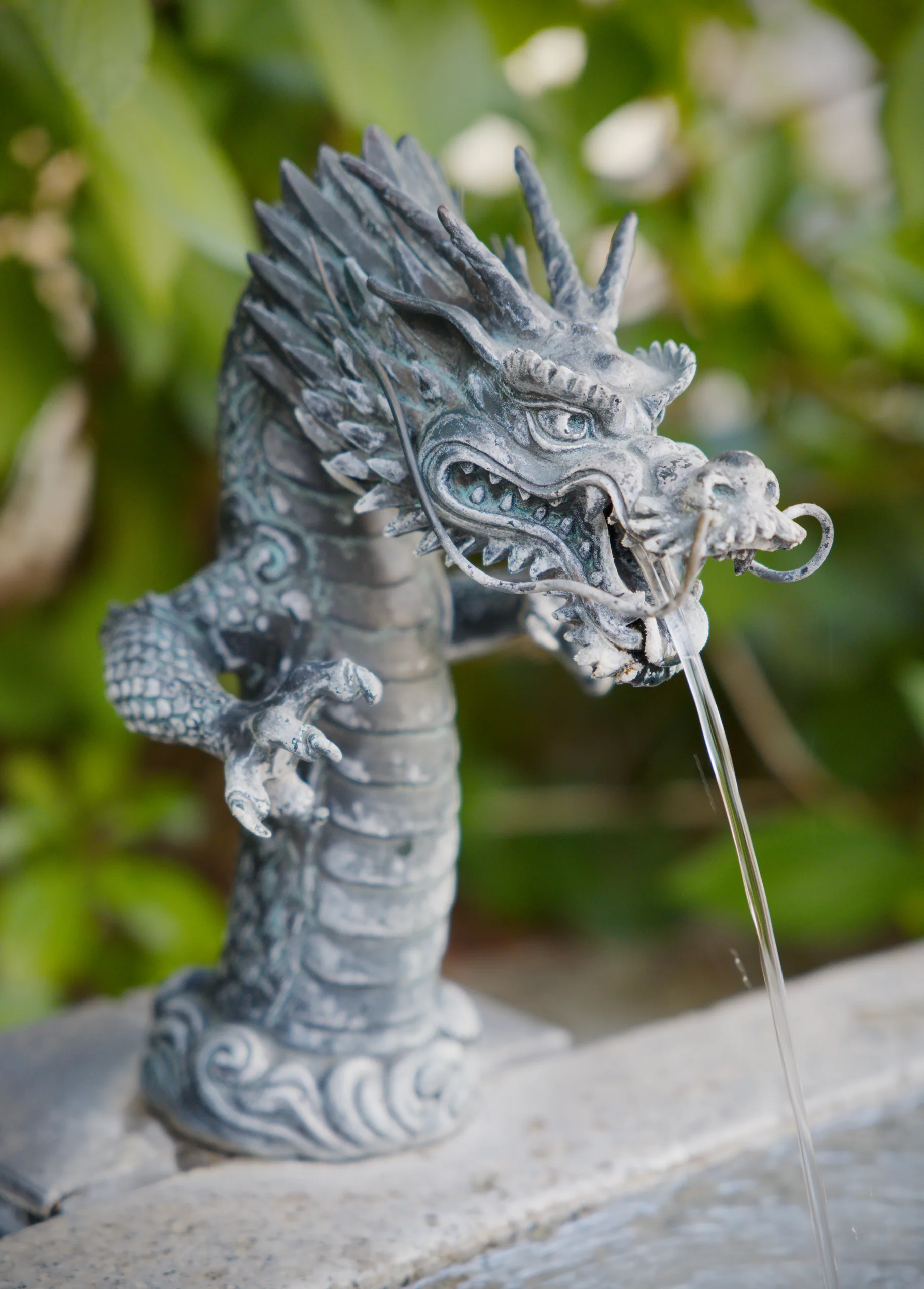 An ornately carved stone dragon sculpture with detailed surface work in profile.