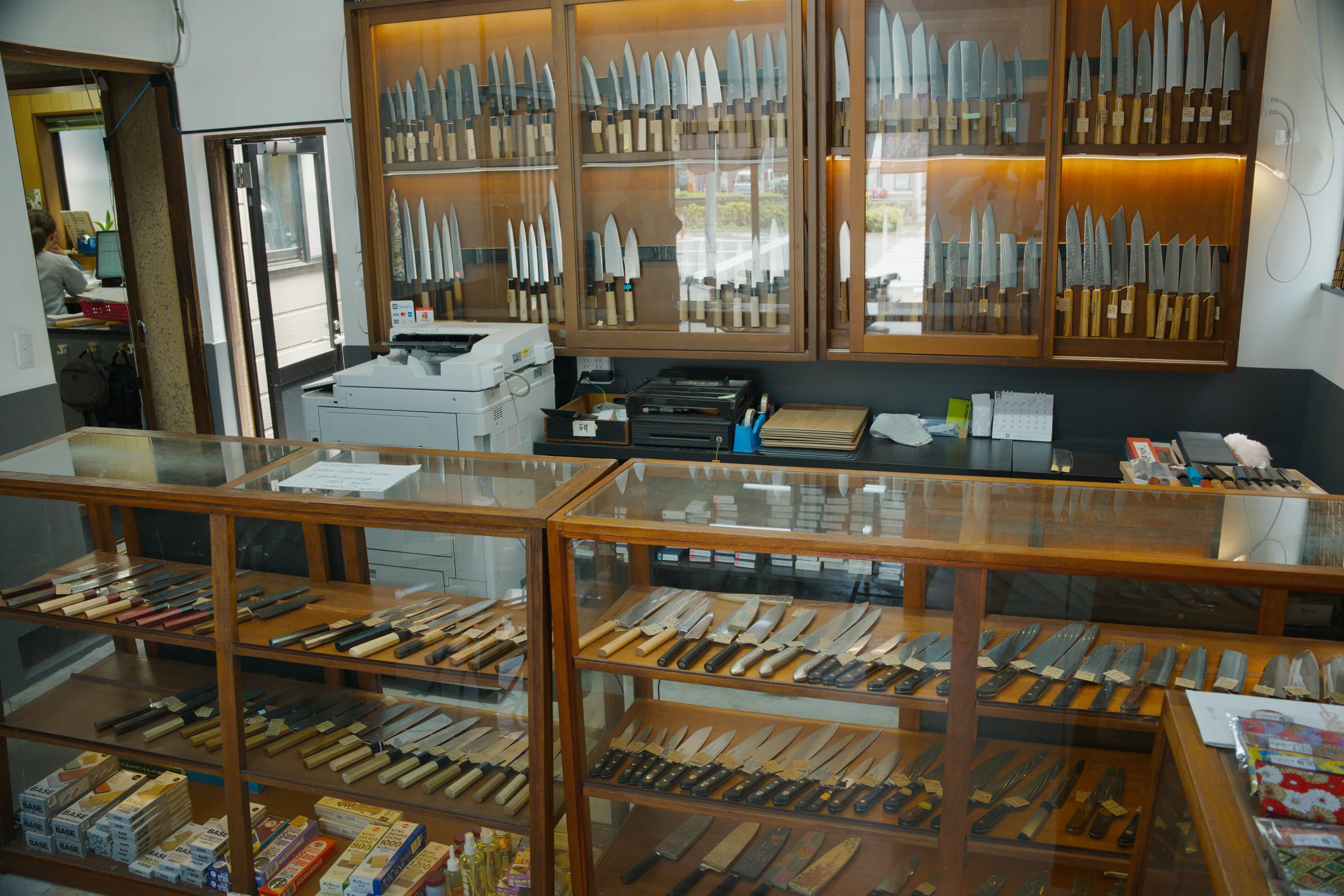 Interior of a workshop or museum with wooden storage cases and glass-fronted cabinets displaying organized rows of tools.