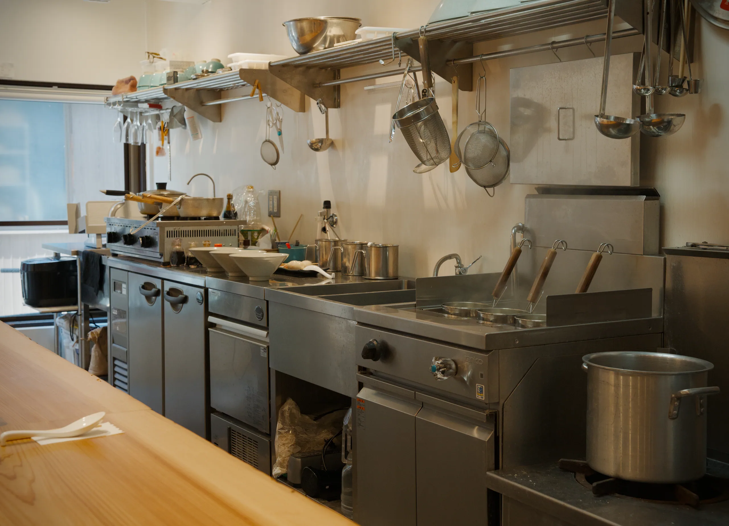 Stainless steel professional kitchen with hanging cookware on a rail.