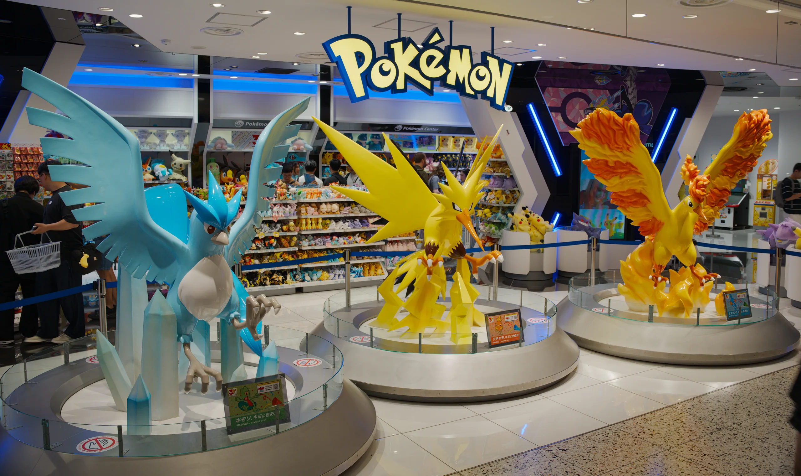 Pokémon retail shop interior with large yellow Pikachu character displays and merchandise shelving.