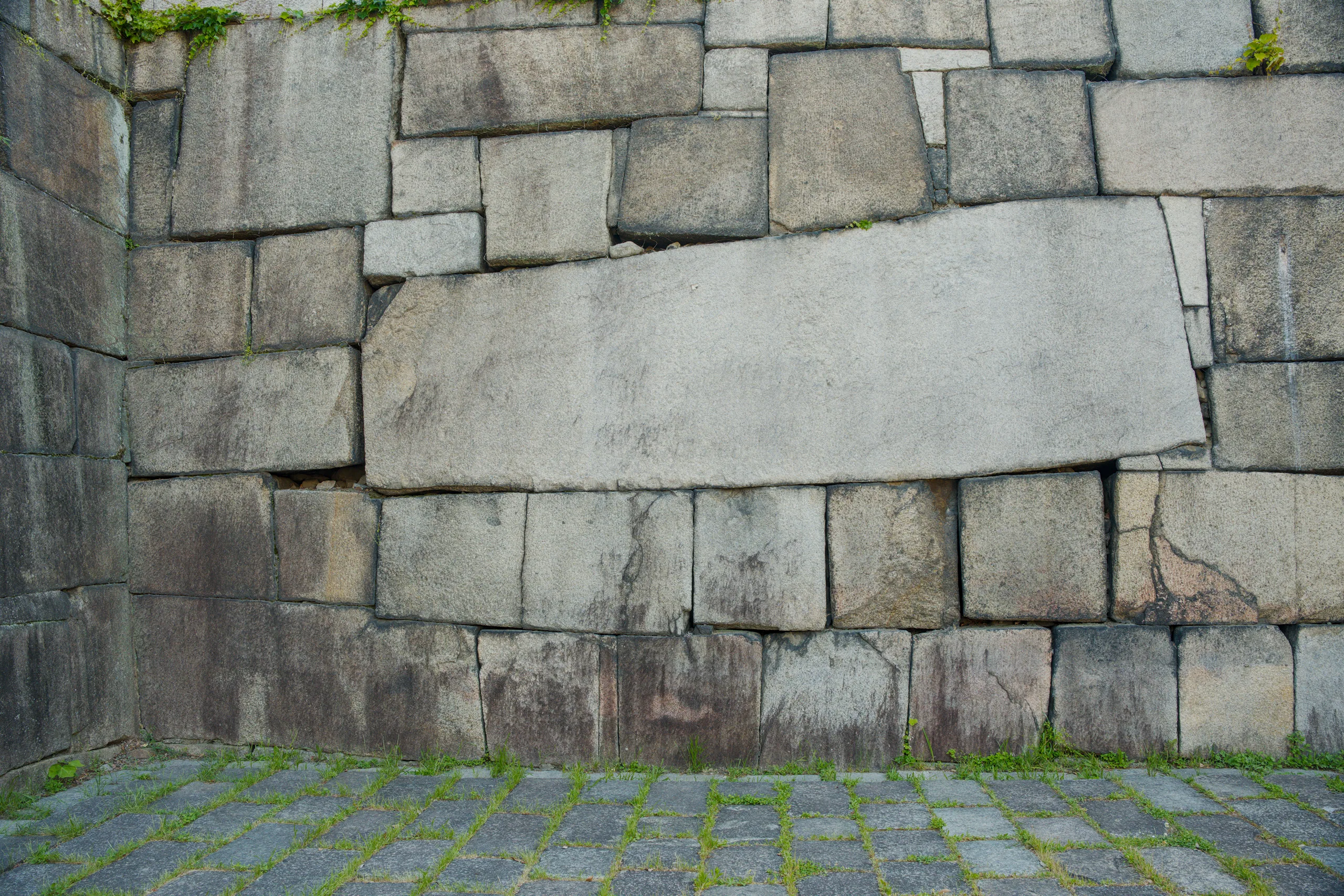 Large stone fortification wall with moss and lichen covering the base blocks.