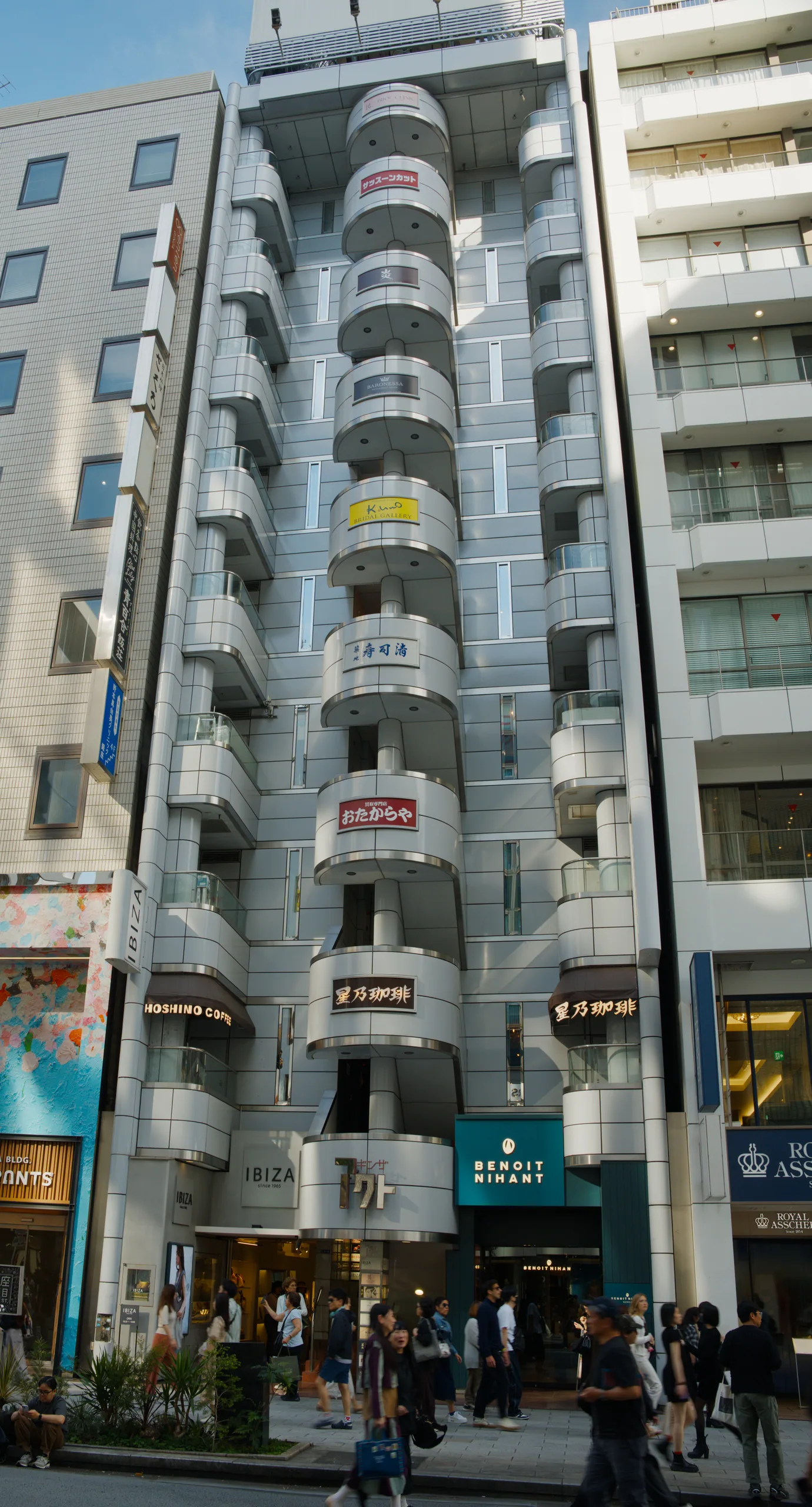Curved residential tower with cantilevered balconies and yellow-and-pink accent panels.