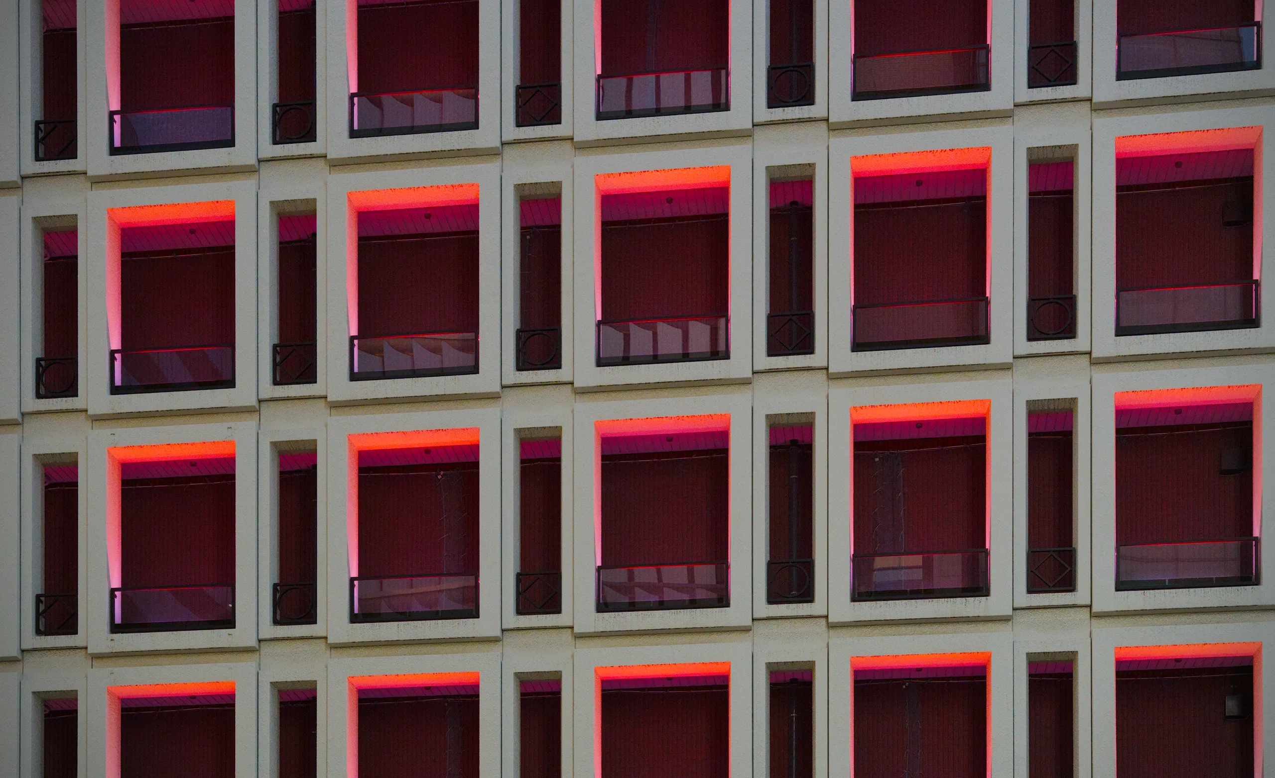 Storefront facade with a grid of red-illuminated square windows in white framing.