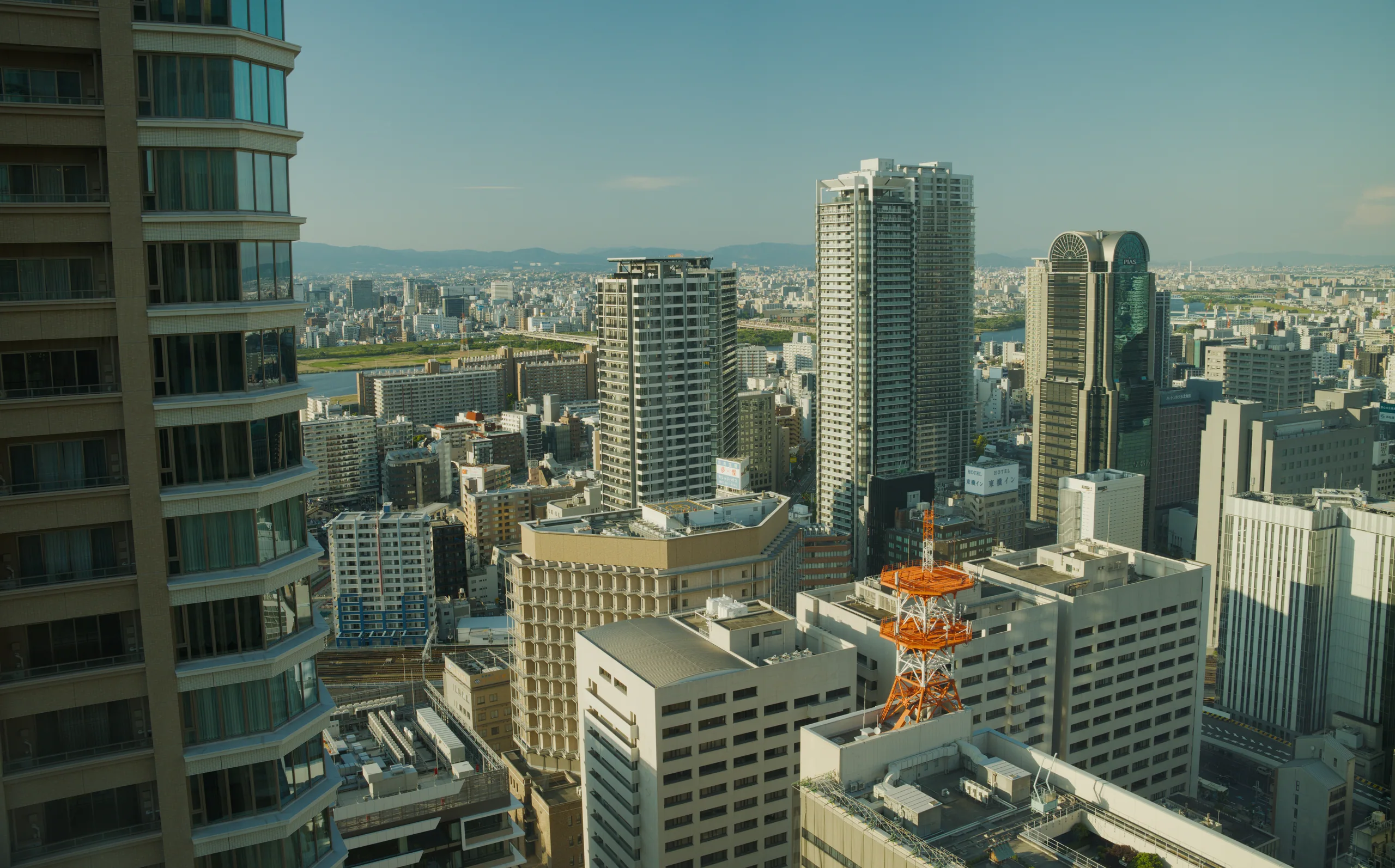 Dense urban skyline with high-rise buildings stretching across the frame, mountains visible on the horizon.