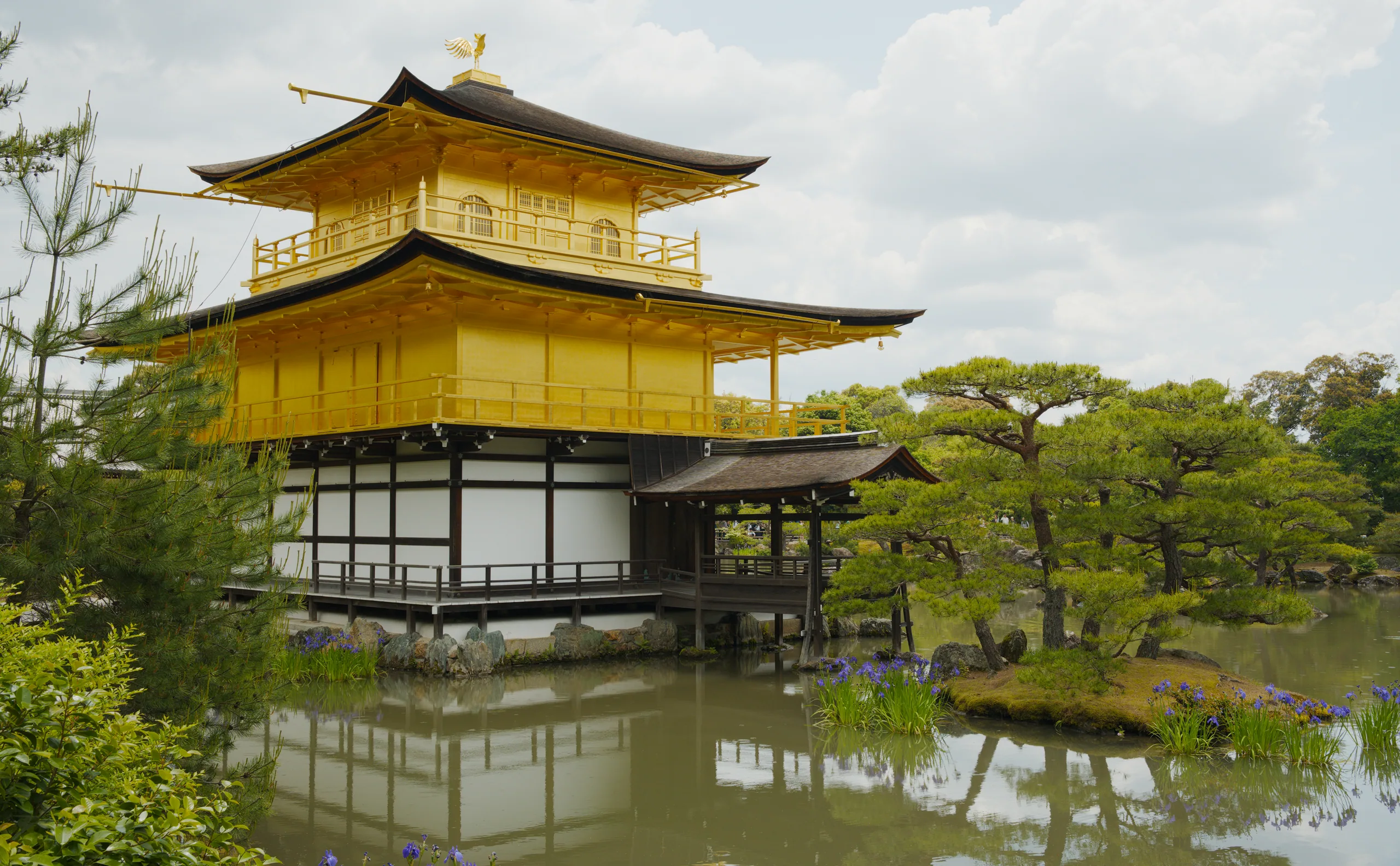 The three-story Golden Pavilion with upturned eaves stands reflected in a garden pond.