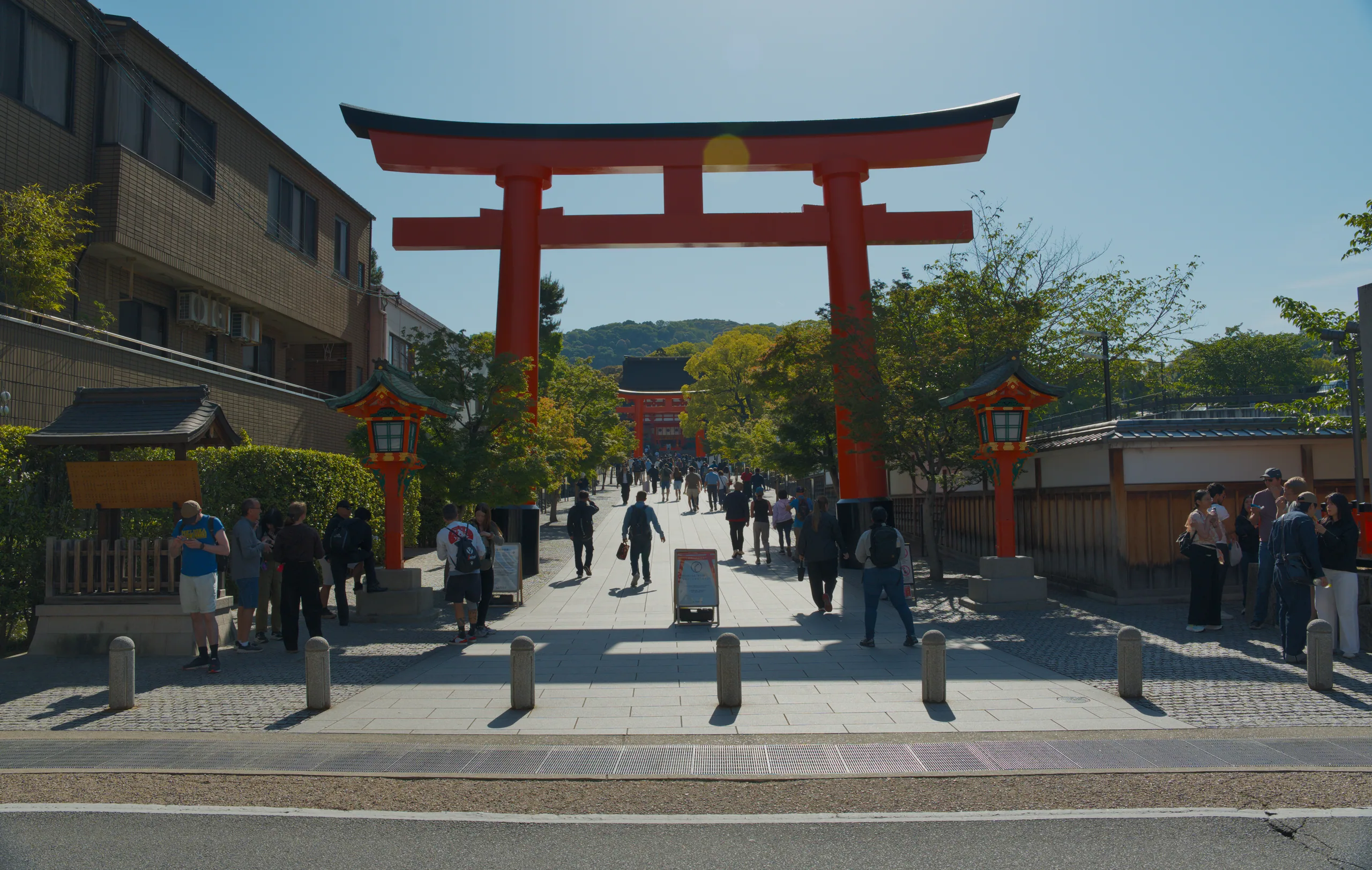 A large red torii gate with people and buildings visible in the courtyard below.
