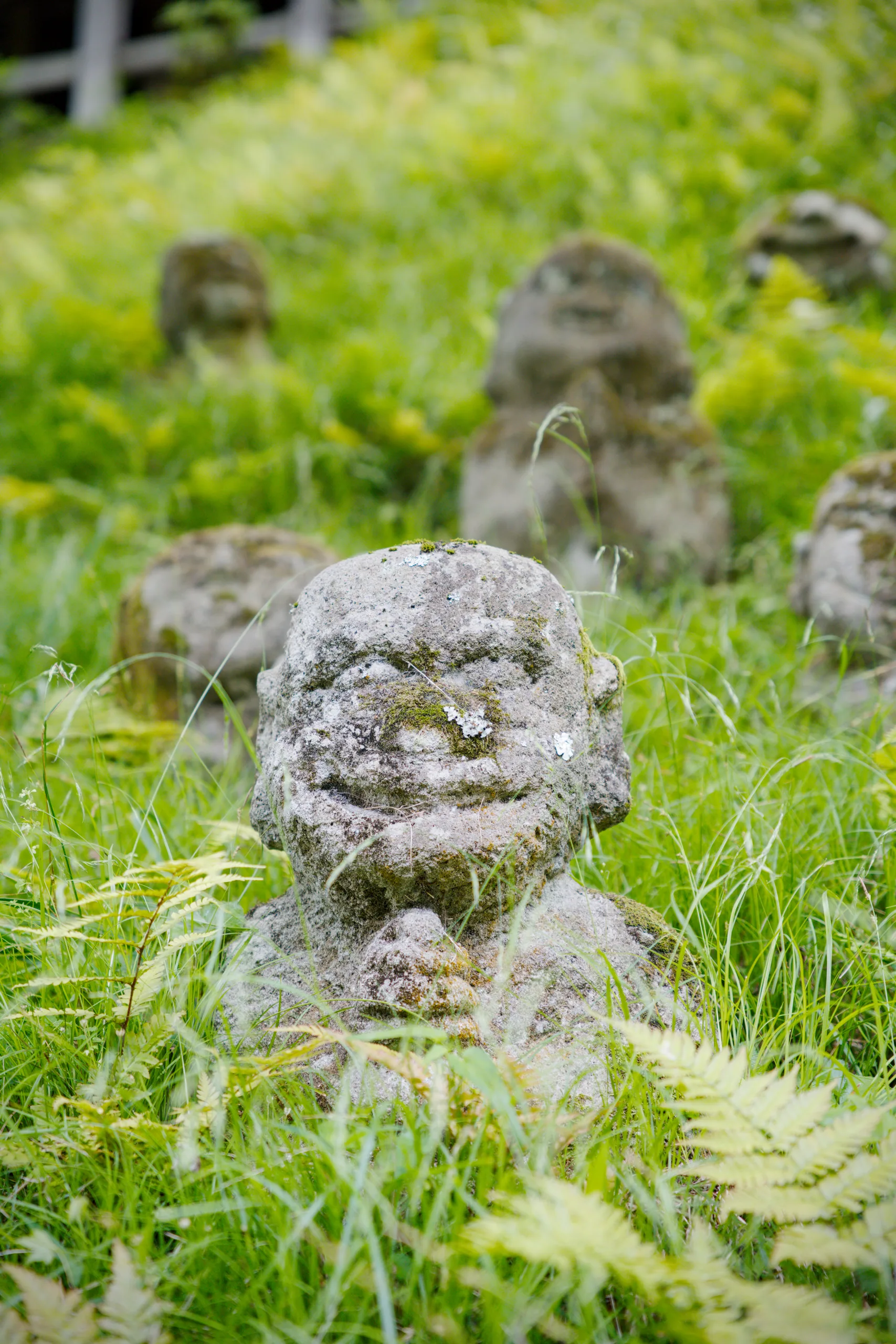 Weathered stone statues with lichen growth on grass.