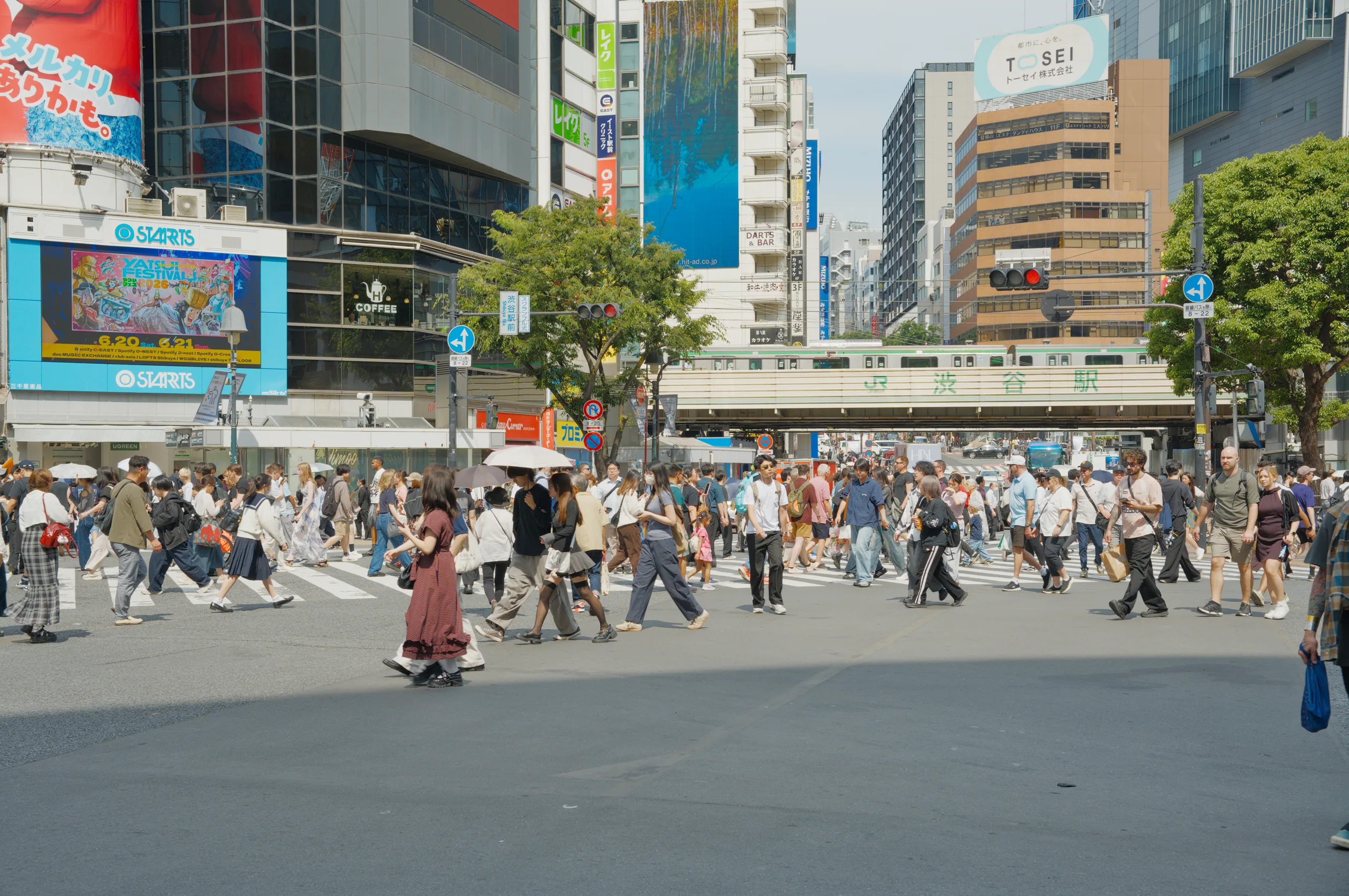 A crowded shopping district with people walking among tall buildings and illuminated signs.