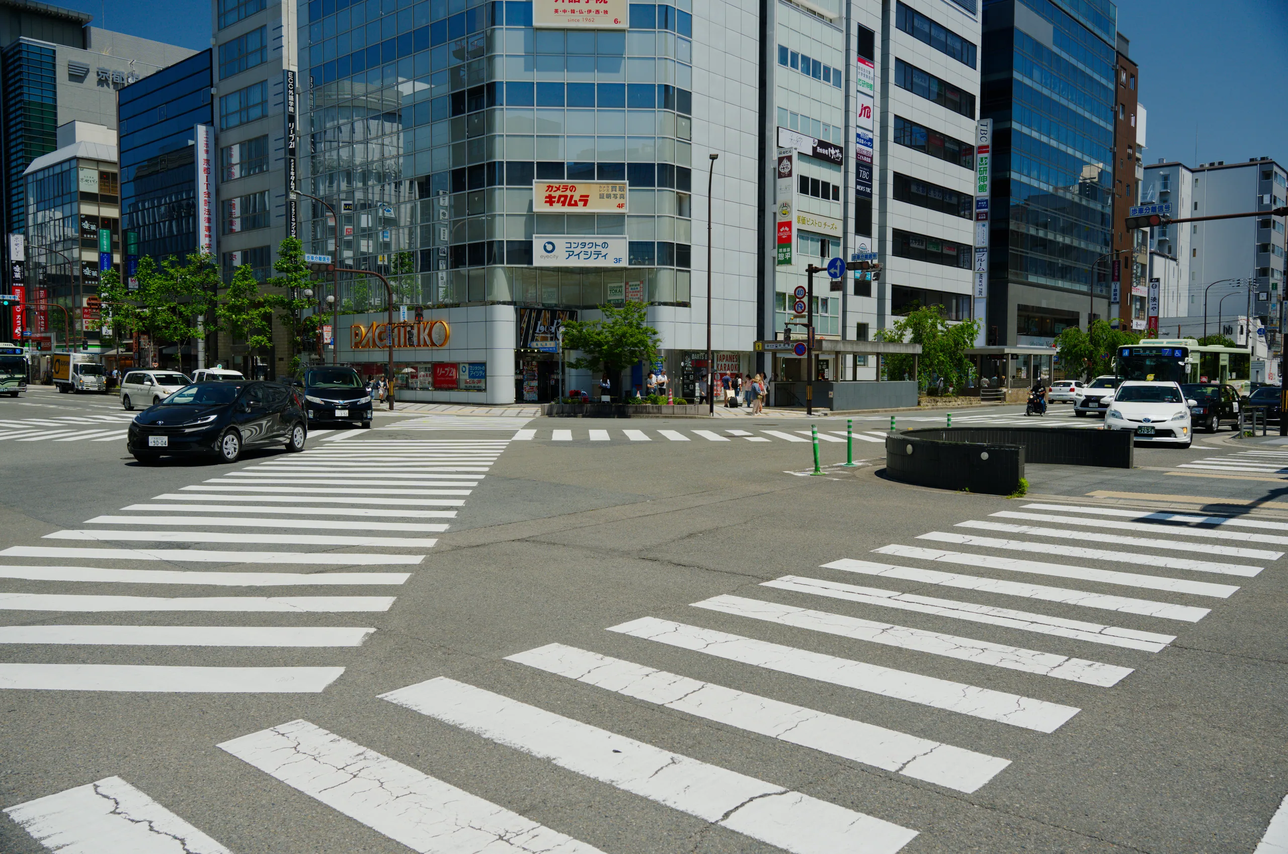 An urban intersection with a zebra crossing, modern office buildings, and parked cars.
