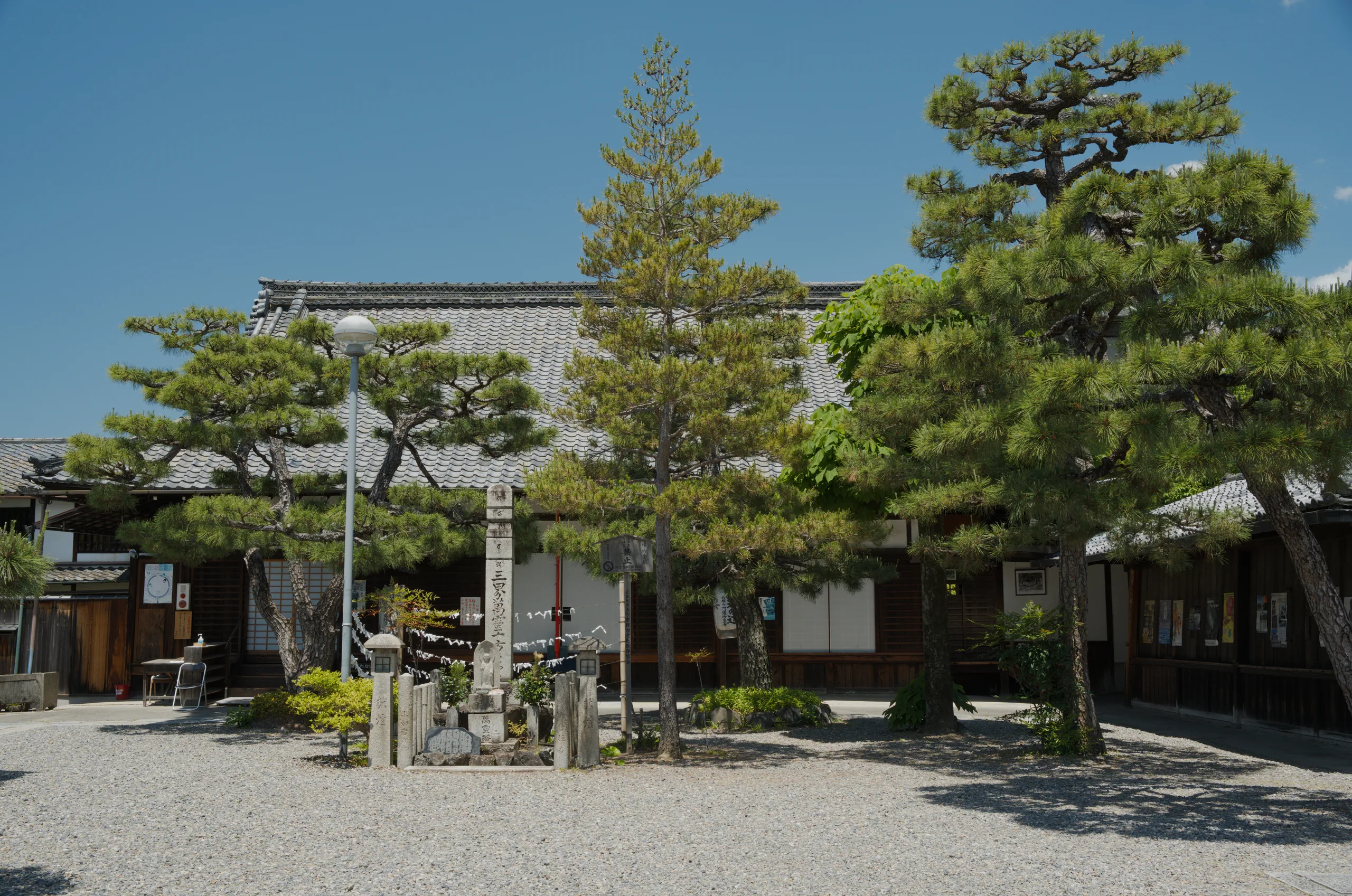 A Japanese temple courtyard with traditional buildings and mature trees in landscaped grounds.