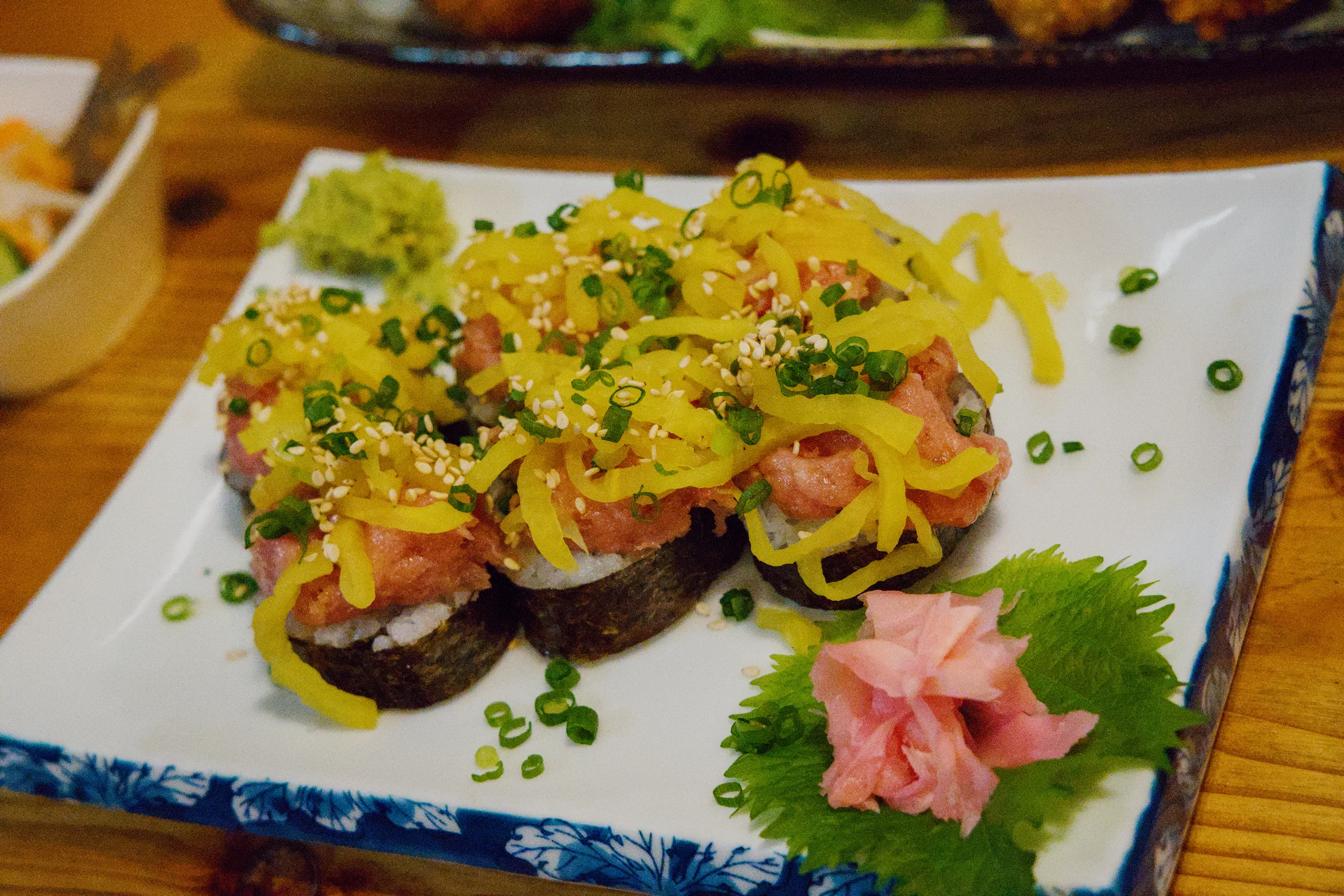 Grilled items topped with yellow sauce and herb garnish on a blue-and-white ceramic plate.