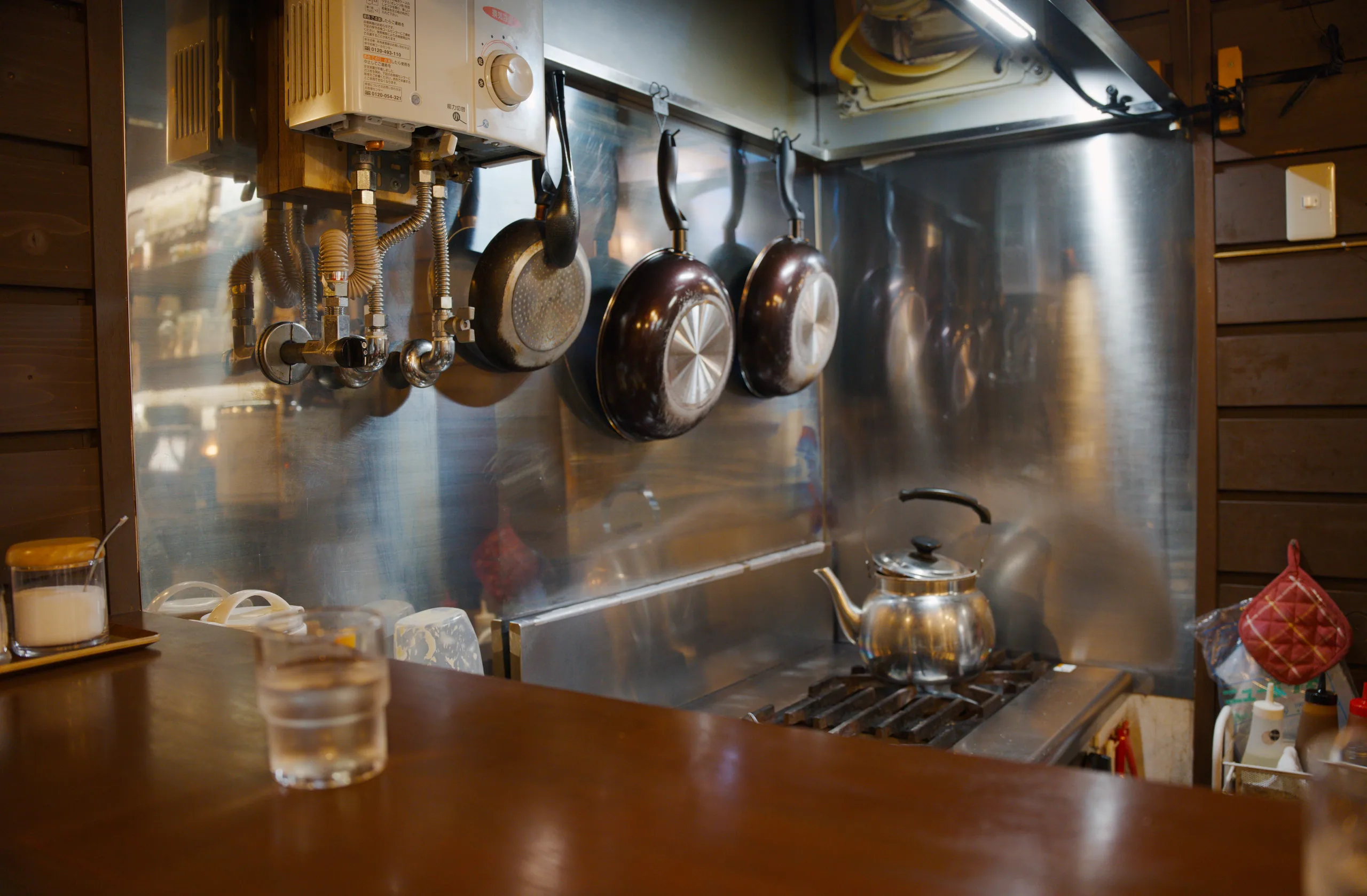 Cookware and utensils hang from hooks on a stainless steel kitchen surface.
