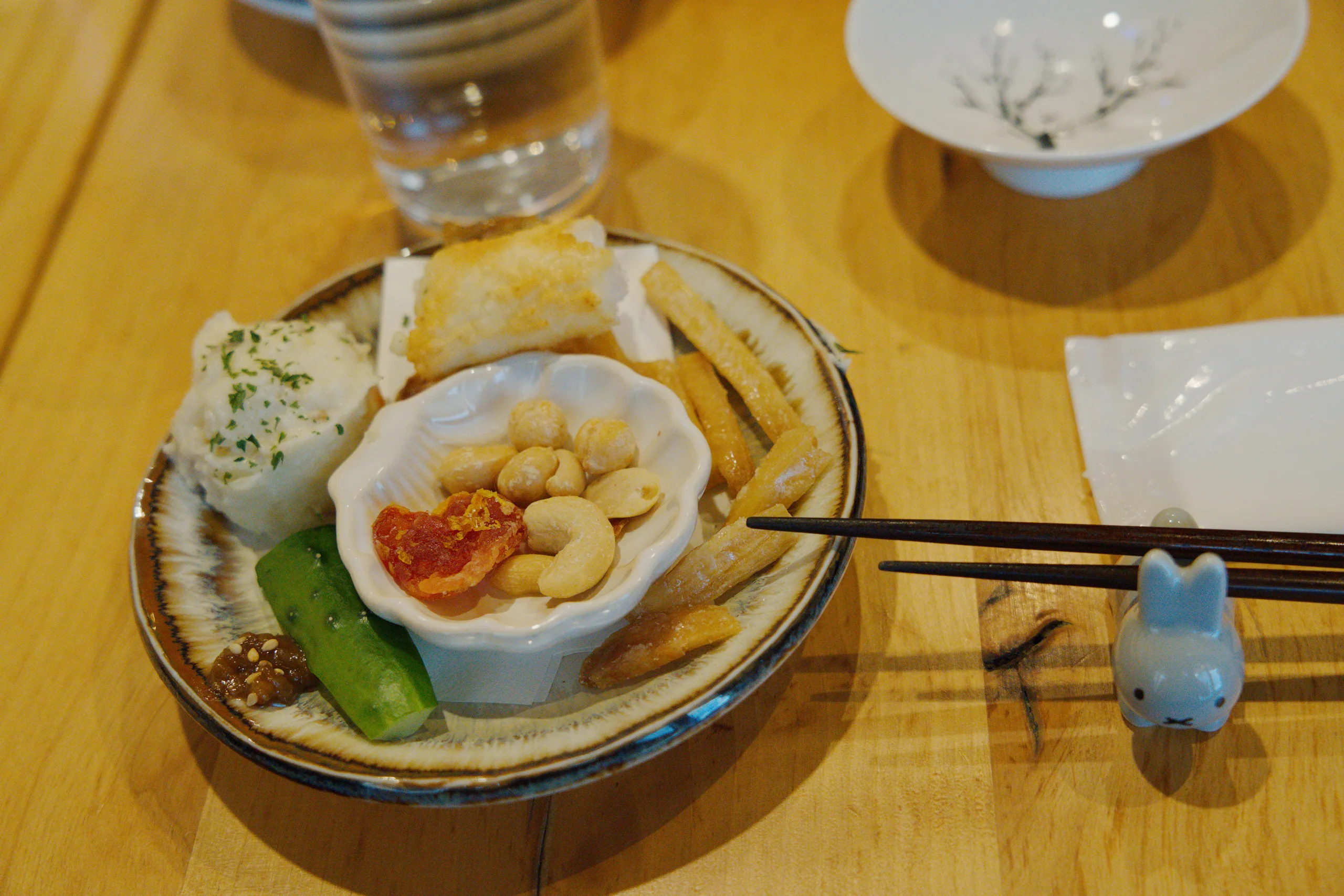 Multiple dishes arranged on a yellow tablecloth, including bowls and plates with noodles and assorted ingredients.