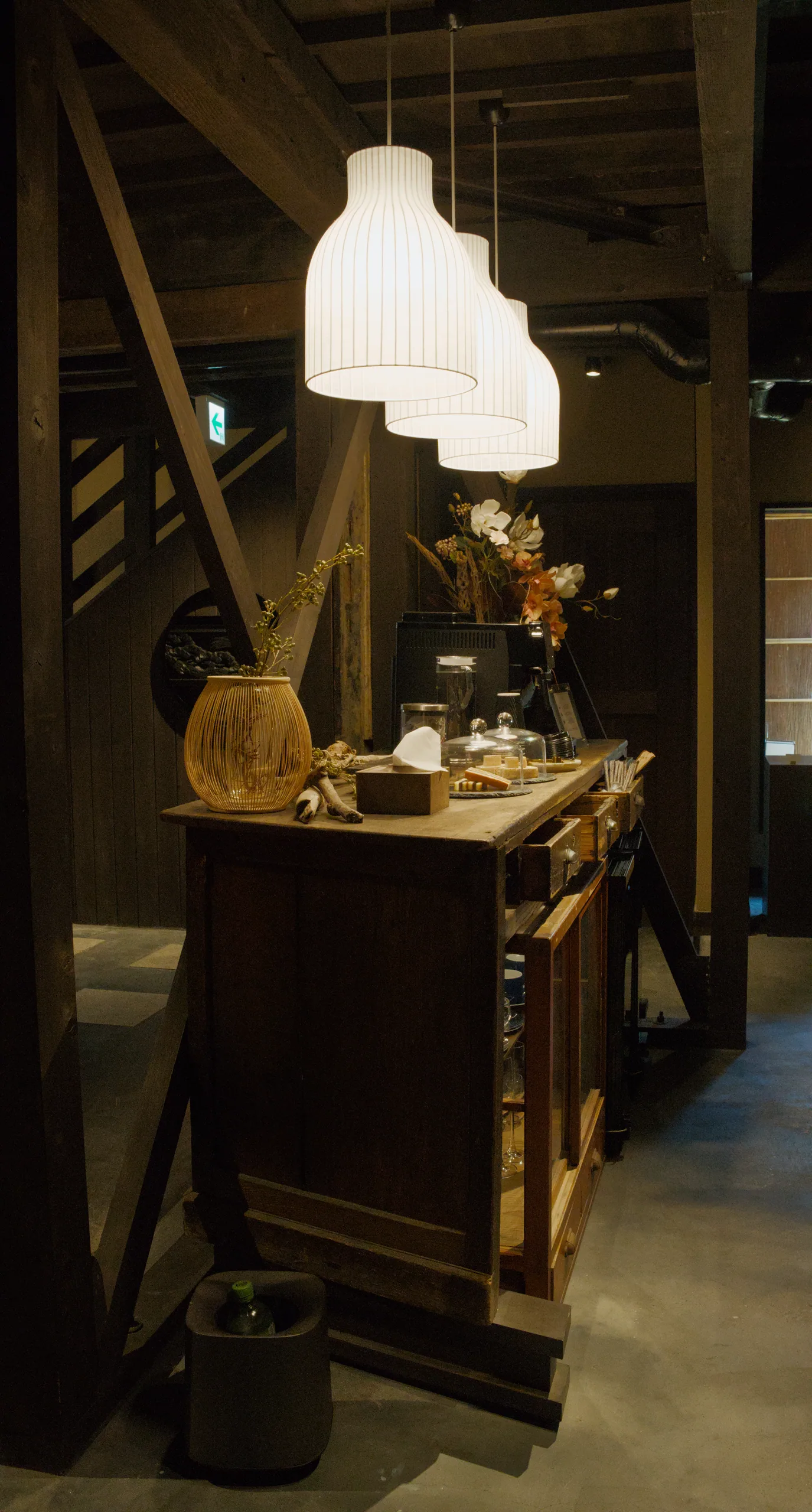An interior display counter with objects on shelves beneath a white pendant light.