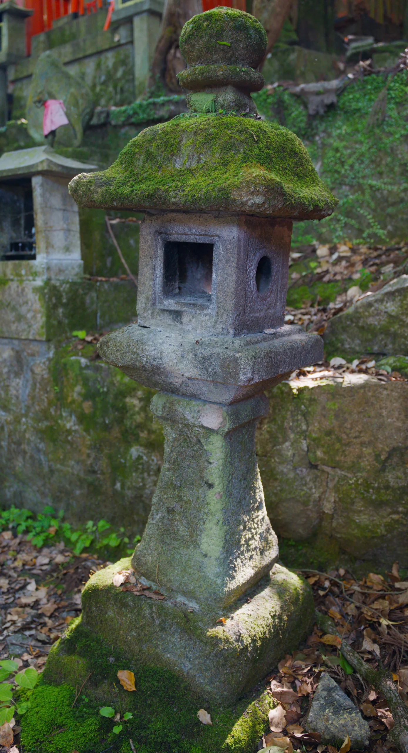 A weathered stone lantern covered in moss, showing texture and age in a temple garden.