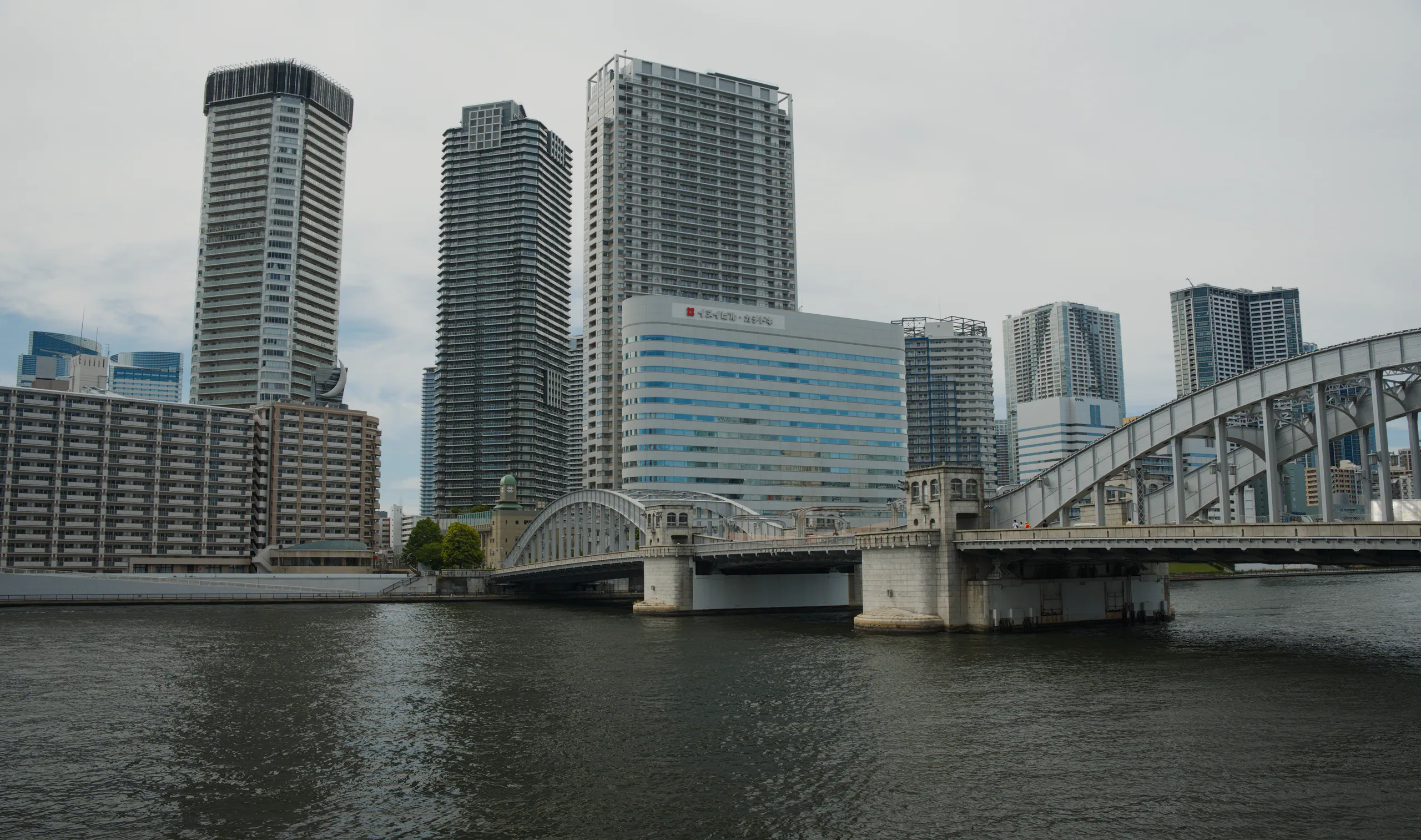 High-rise towers reflected in a river with a bridge connecting the cityscape across the water.