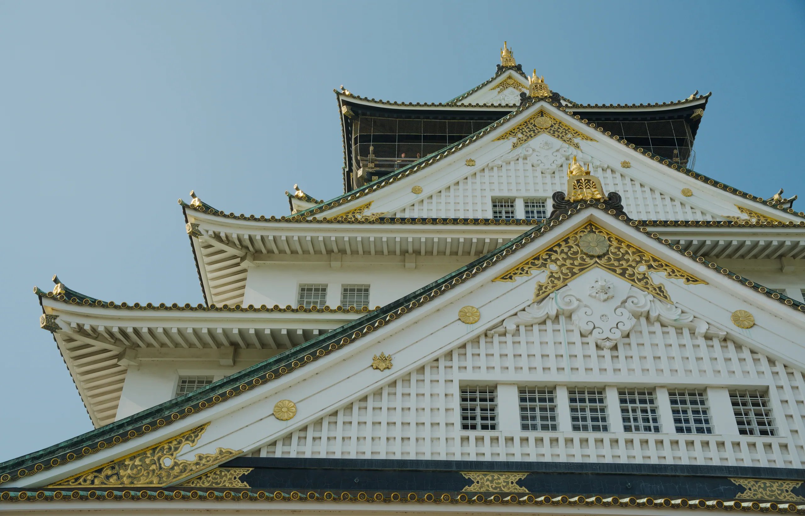 Stacked white and gold castle roofs with upturned eaves and gold-trimmed gables.