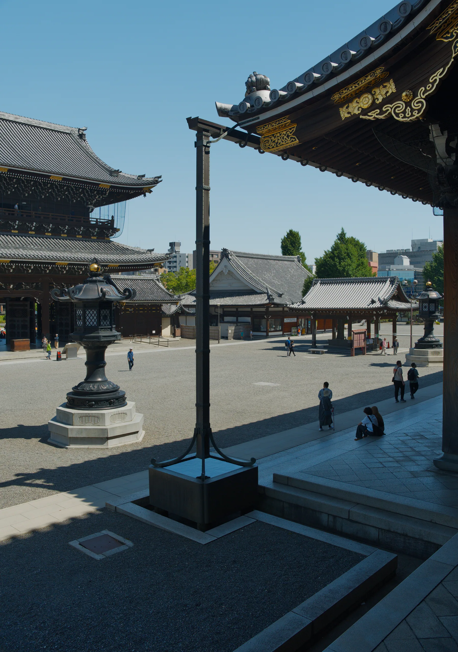 A temple courtyard with ornate roof eaves, a metal incense burner in the foreground, and clustered traditional buildings.