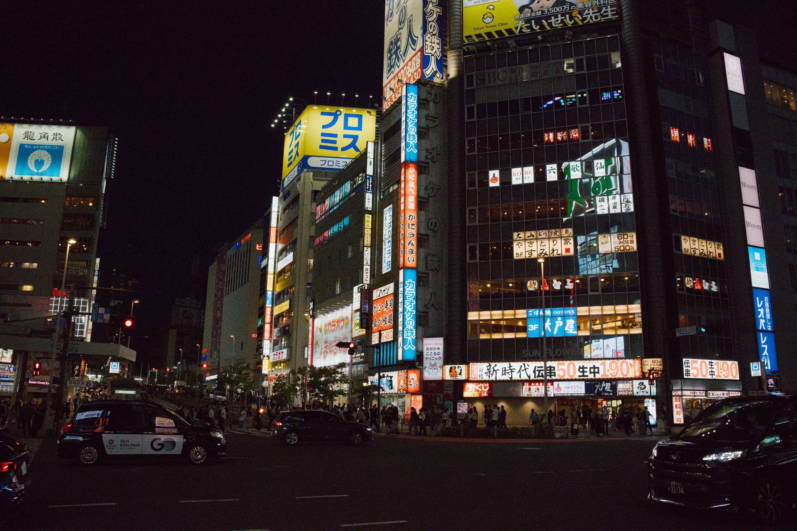 Illuminated storefronts and neon signs on a busy shopping street at night.
