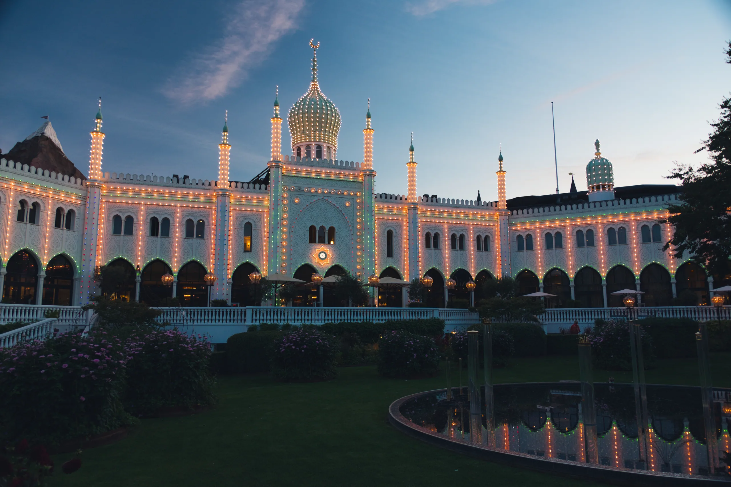 The Moorish pavilion at Tivoli outlined in hundreds of bulbs at dusk, its lawn and reflecting pool in front.